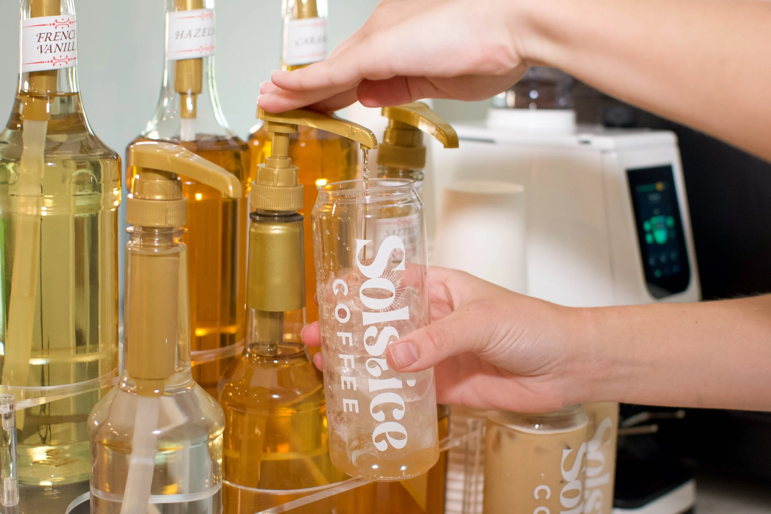 Coffee syrup being pumped into custom latte can on solstice coffee cart to make an espresso based latte.