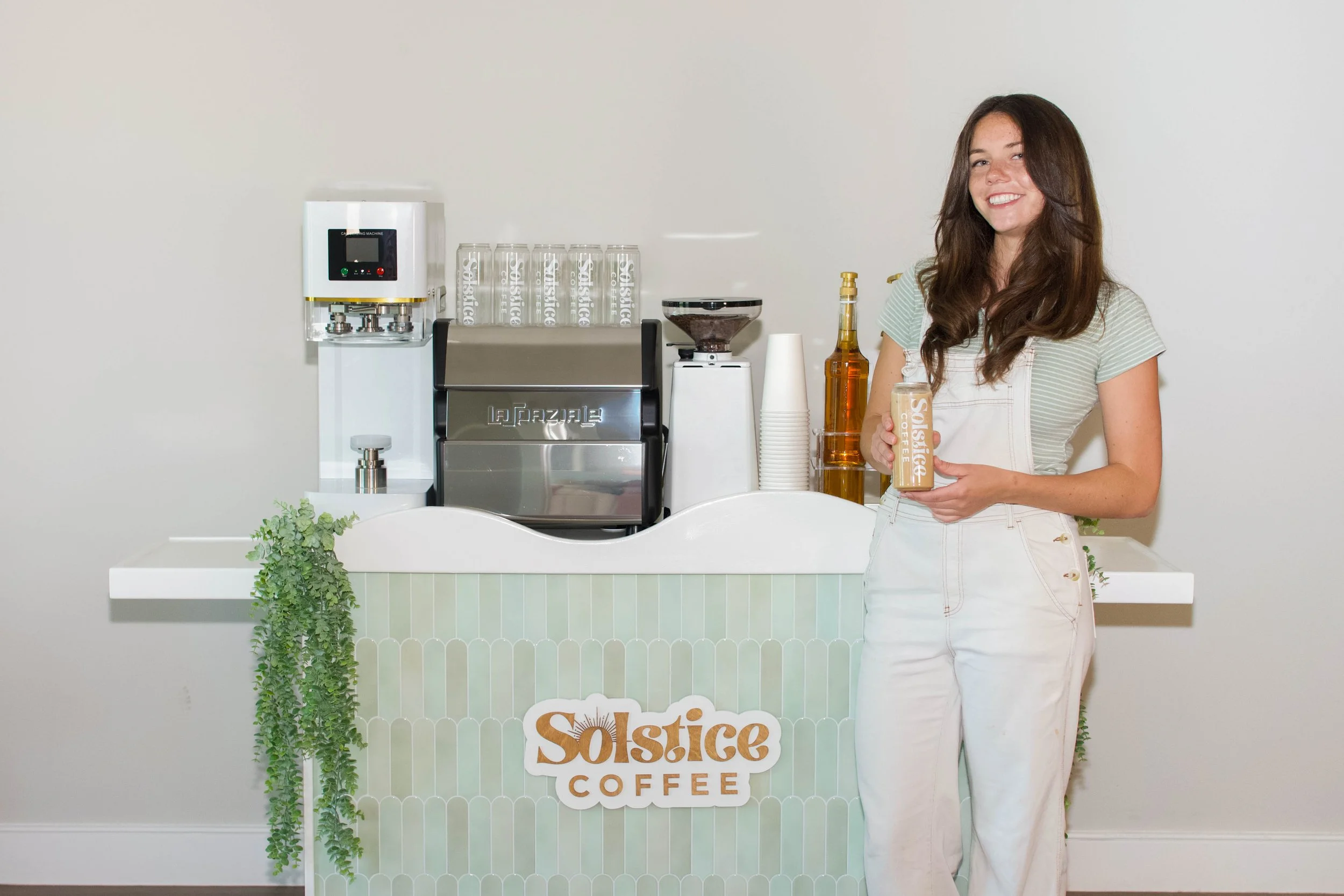 barista holding canned latte in front of coffee cart.