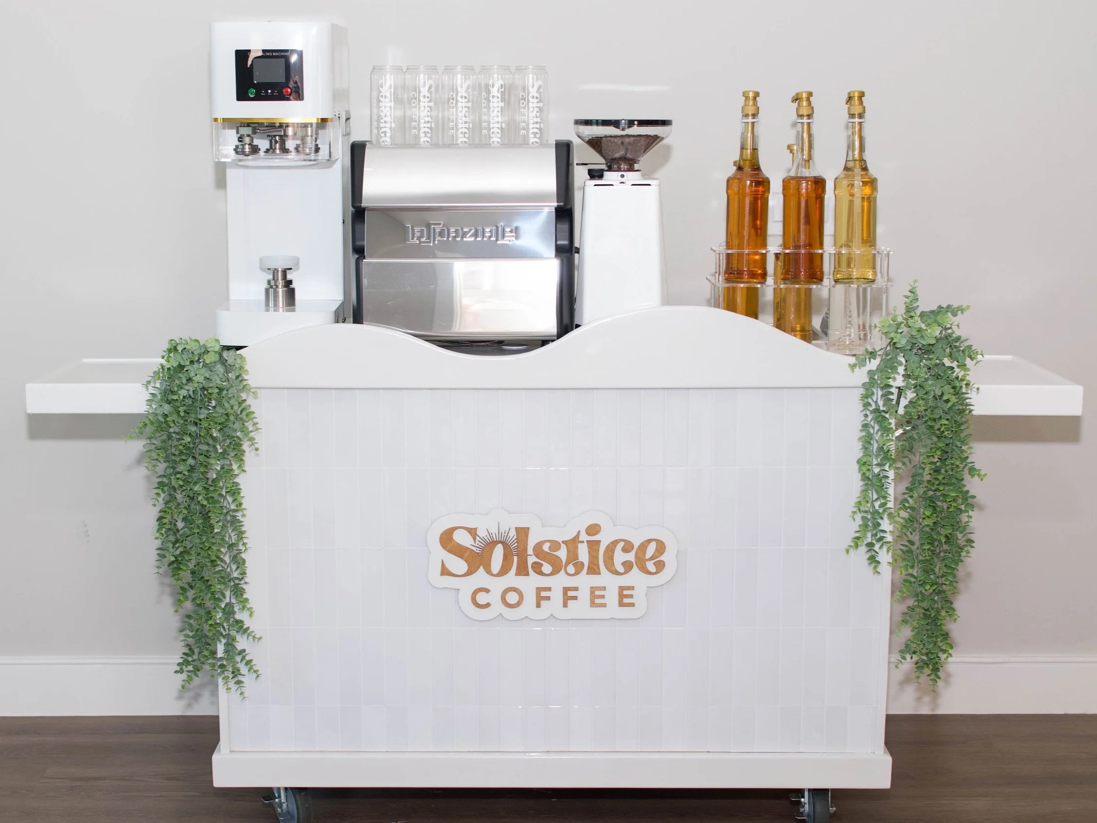 a white mobile coffee cart used to serve espresso drinks and canned coffee.
