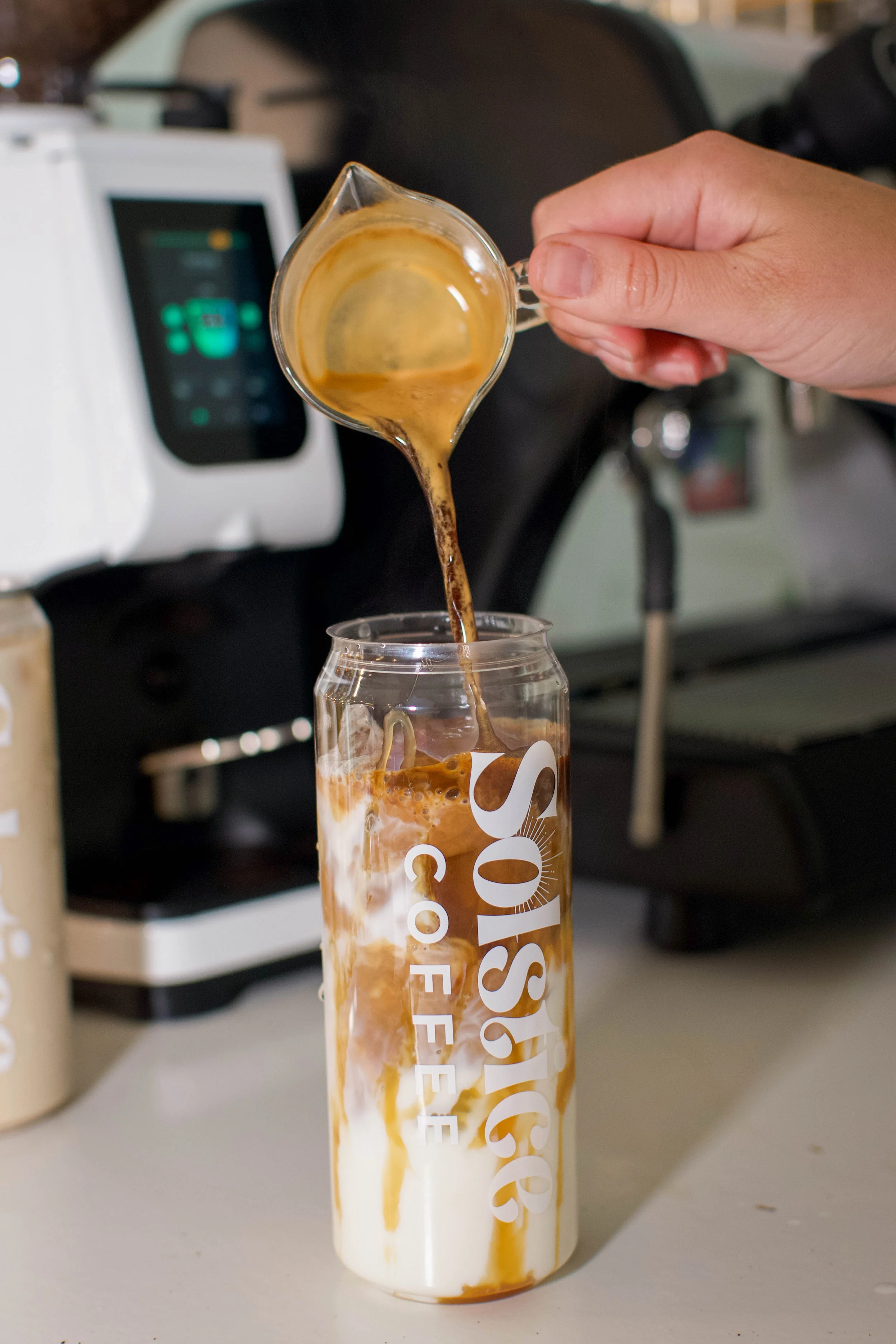 Espresso shot being poured into a custom canned latte drink on solstice coffee cart.