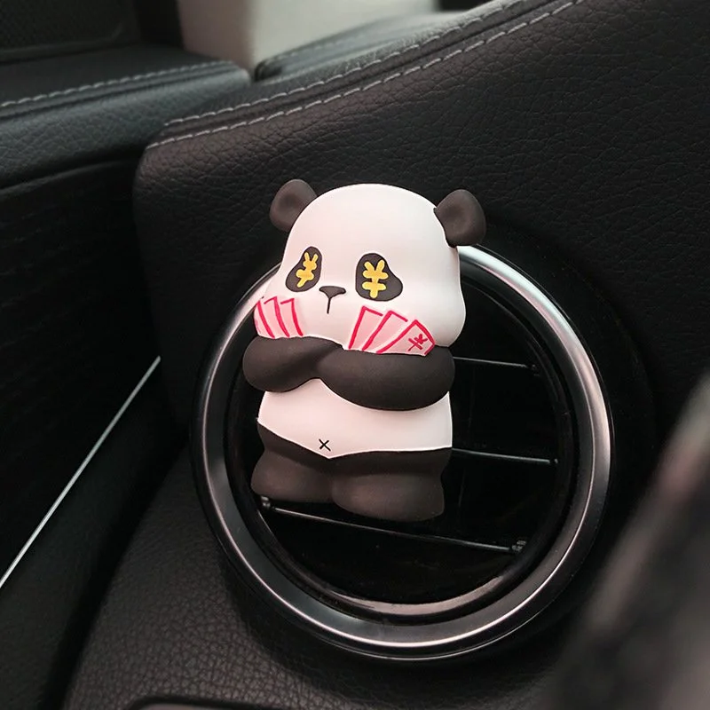 A panda-shaped air freshener with closed eyes holding red envelopes, attached to a car vent.