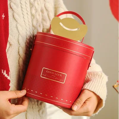 Person holding a red gift box with a gold handle and a label that says 'Good Luck'.