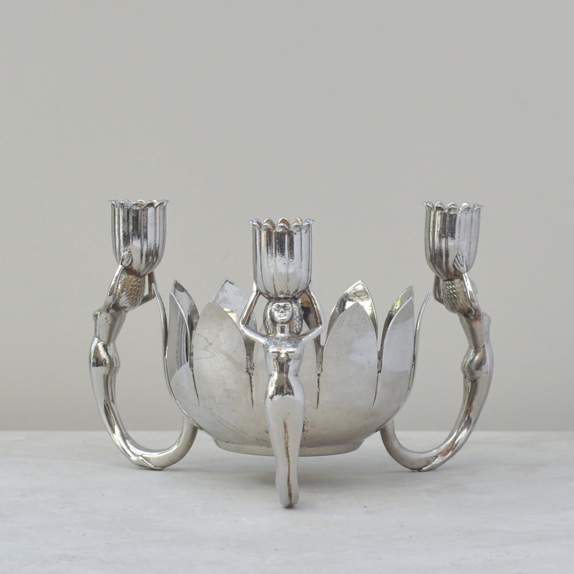 Side angle of the mid-century silver lotus bowl with stylised female candle holders.