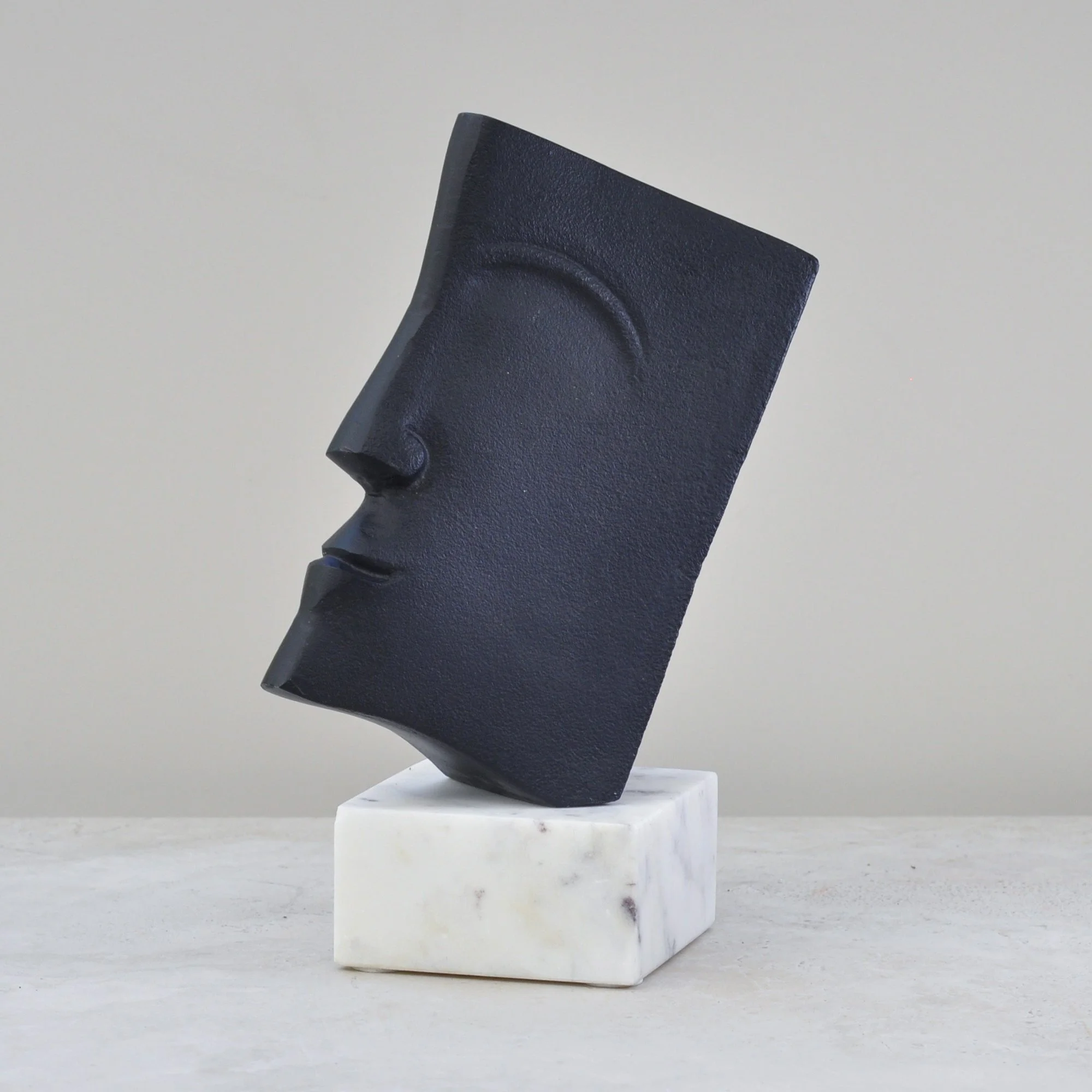 Side profile of modernist black metal sculptural object on marble base