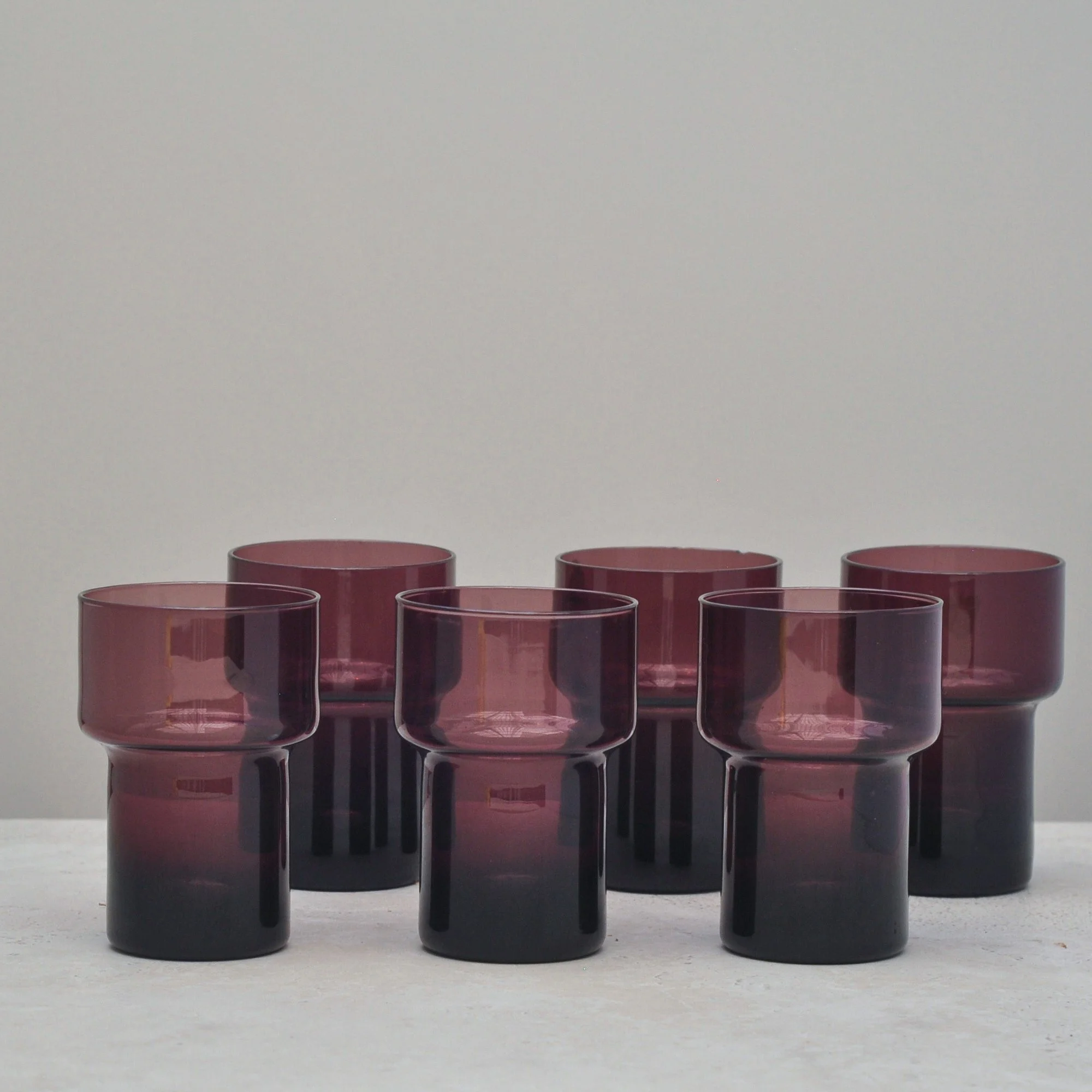 “Set of six vintage aubergine glass tumblers arranged together, highlighting their deep purple tone and clean mid-century form.”