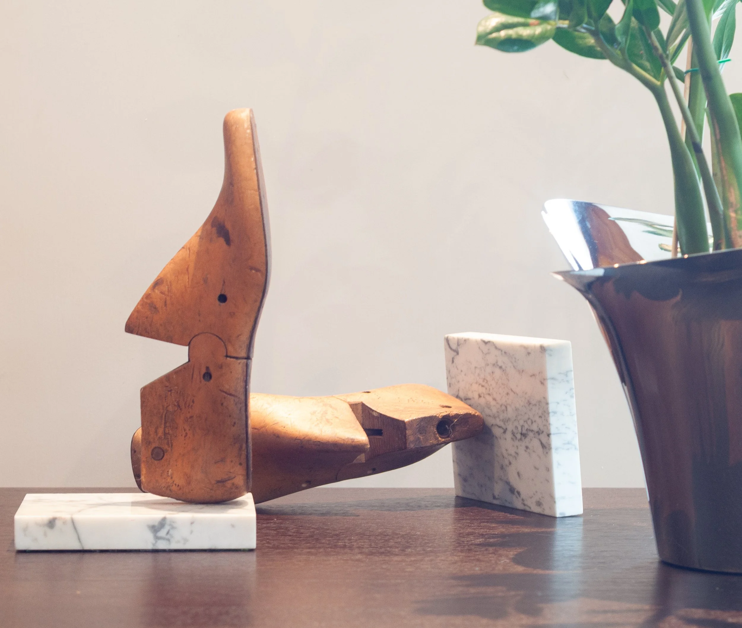Vintage wooden shoe lasts mounted on marble blocks, styled with a silver planter and fresh greenery — Again by Clare.