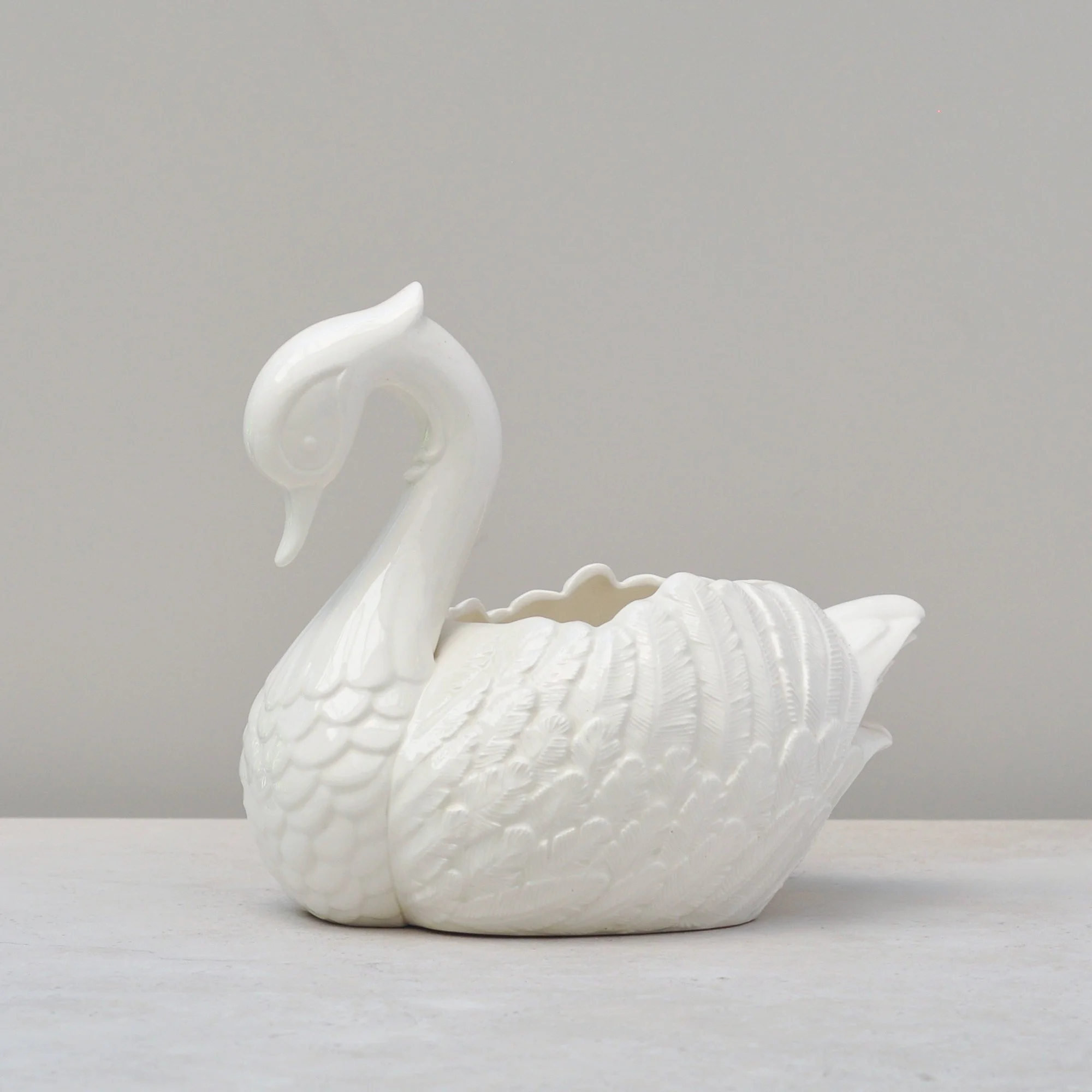 Vintage handmade ceramic swan bowl from 1987, front angle on grey-beige background.