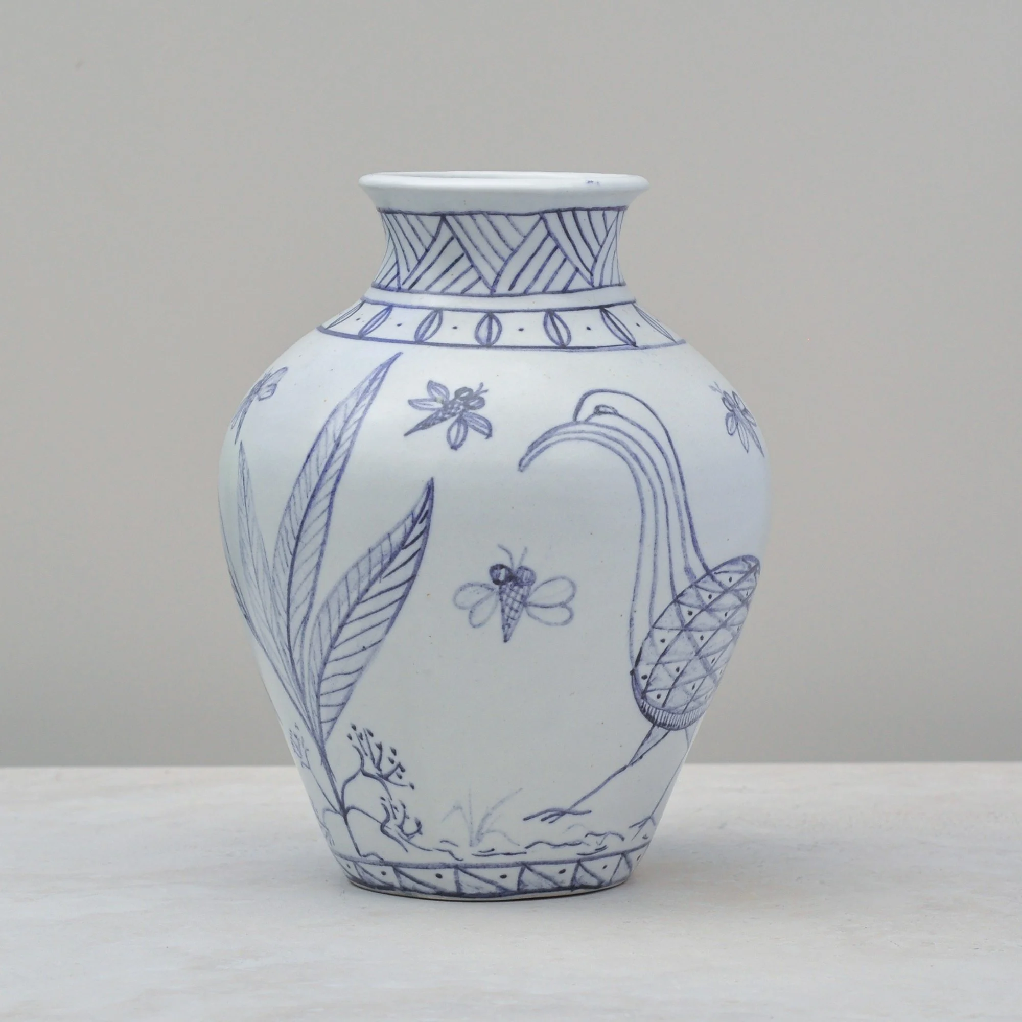 Front view of a blue and white vintage vase featuring a stylised bird motif and delicate floral detailing.