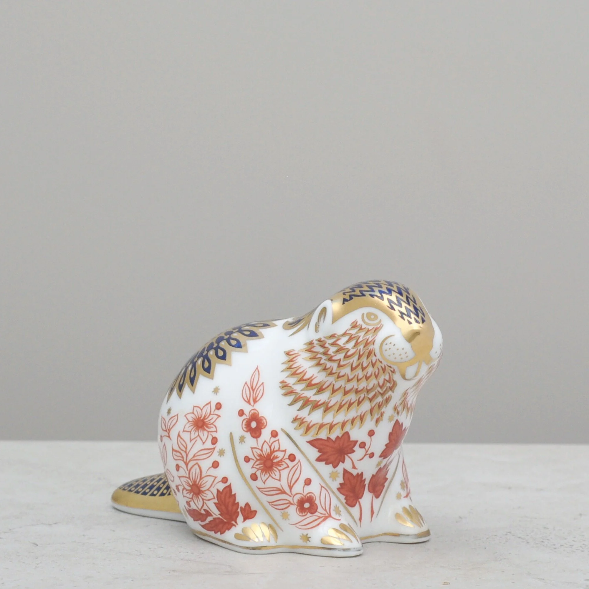 Right-side profile of a Royal Crown Derby beaver paperweight showing the ornate gold, red and blue patterning.