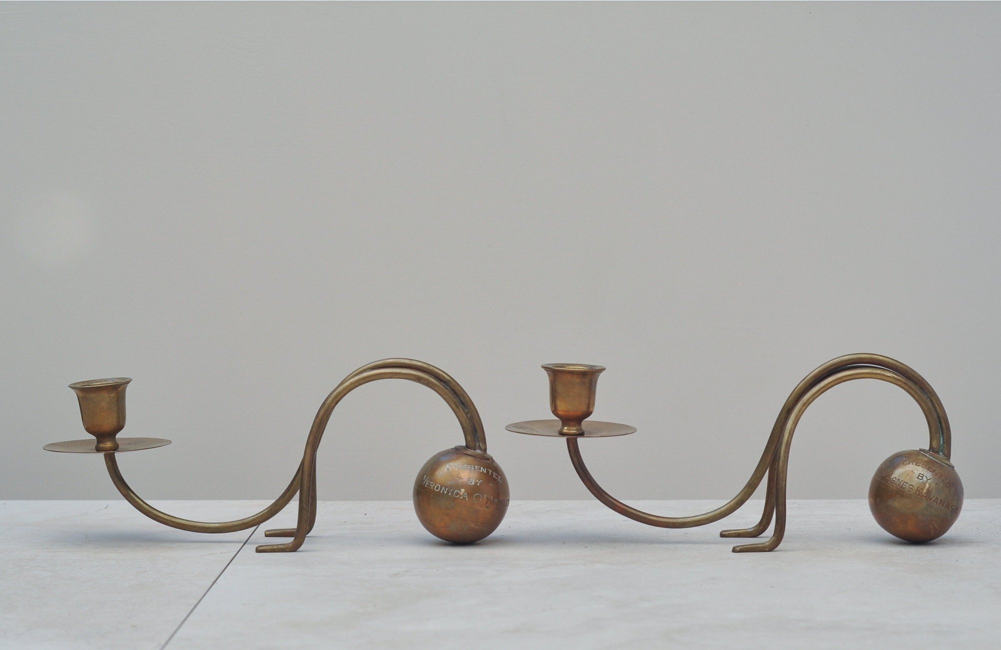 Pair of vintage brass sculptural candlesticks made from Presented By brass balls, front view.