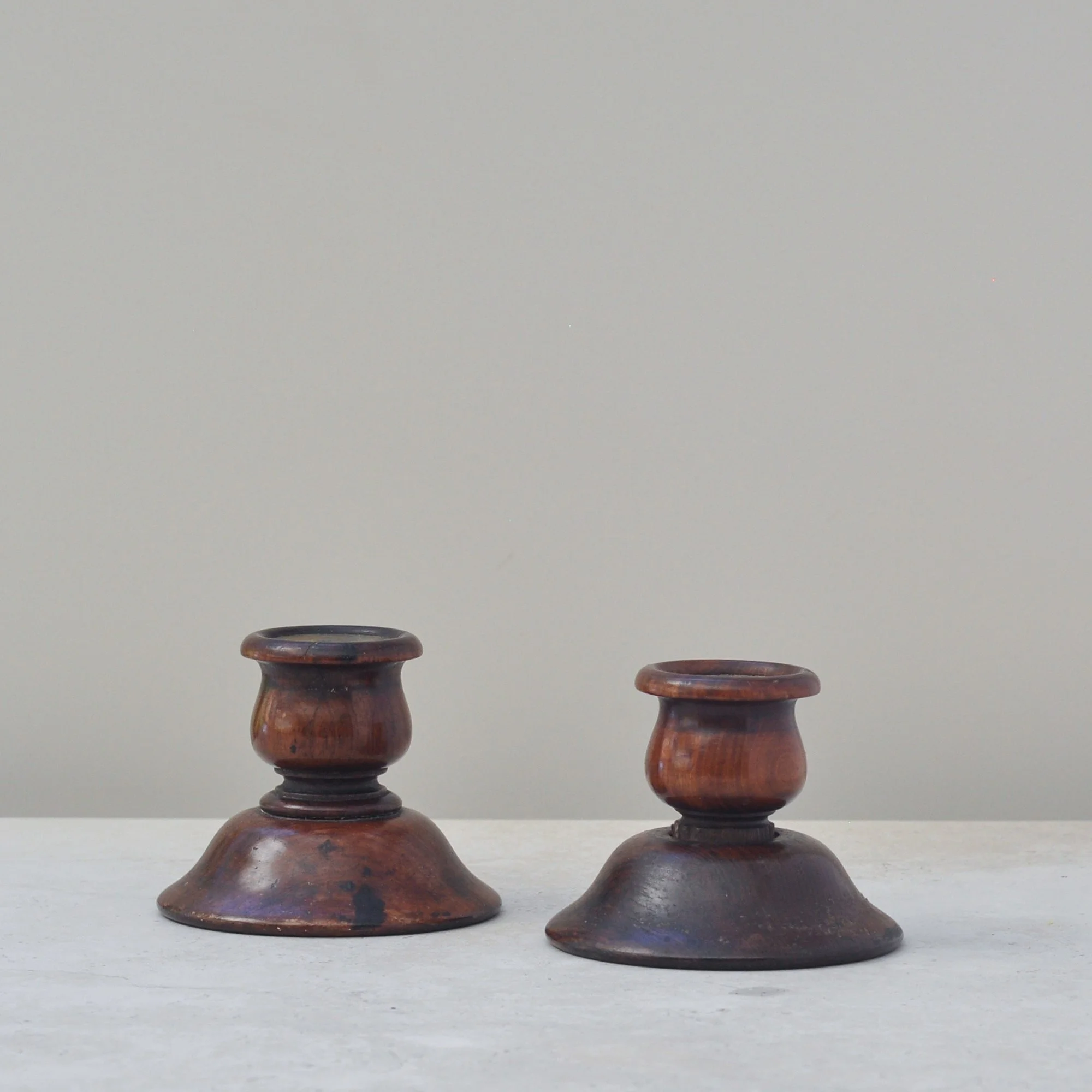 Close front angle of antique turned wood candlesticks displaying aged wood tones and shape.