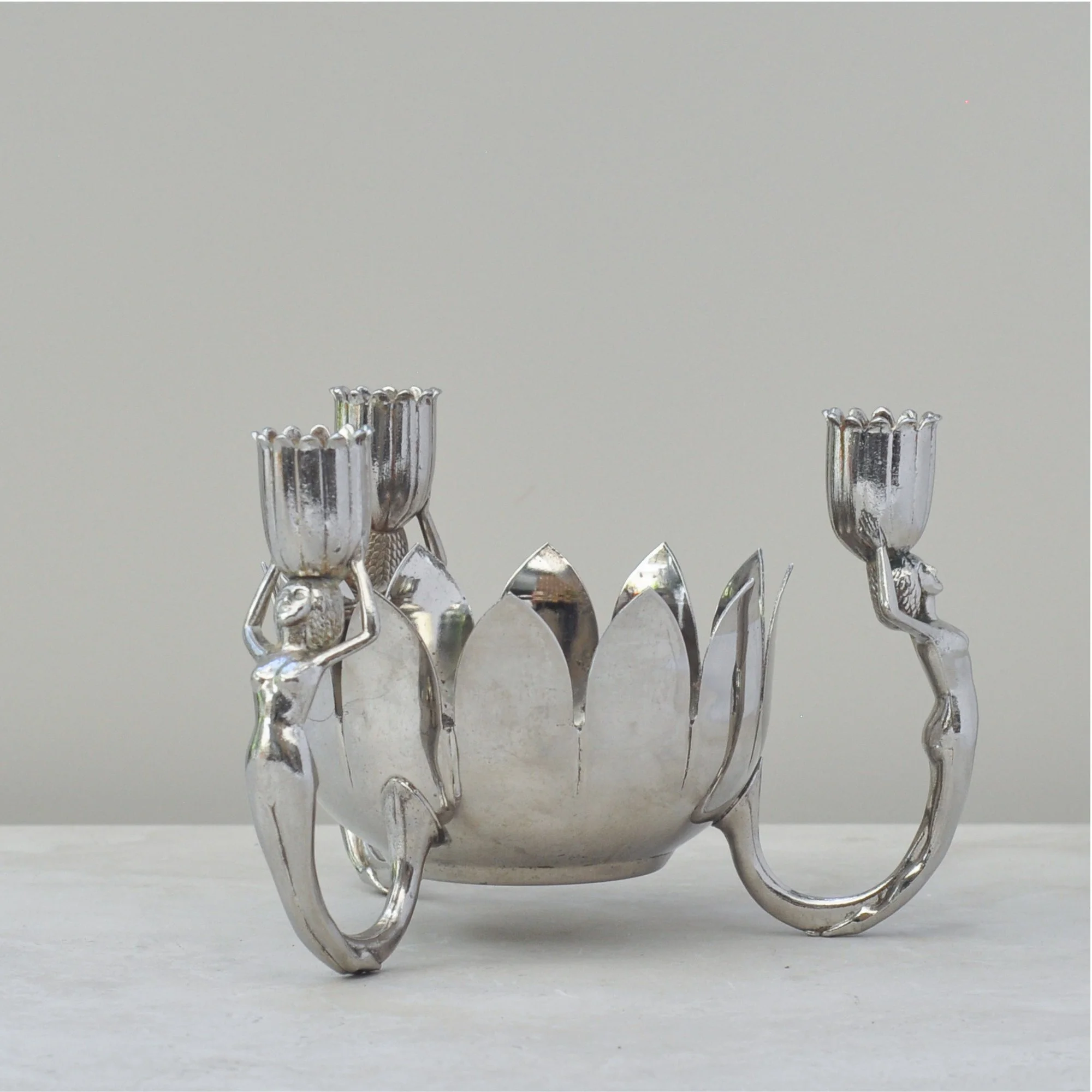 Side angle of the mid-century silver lotus bowl with stylised female candle holders.