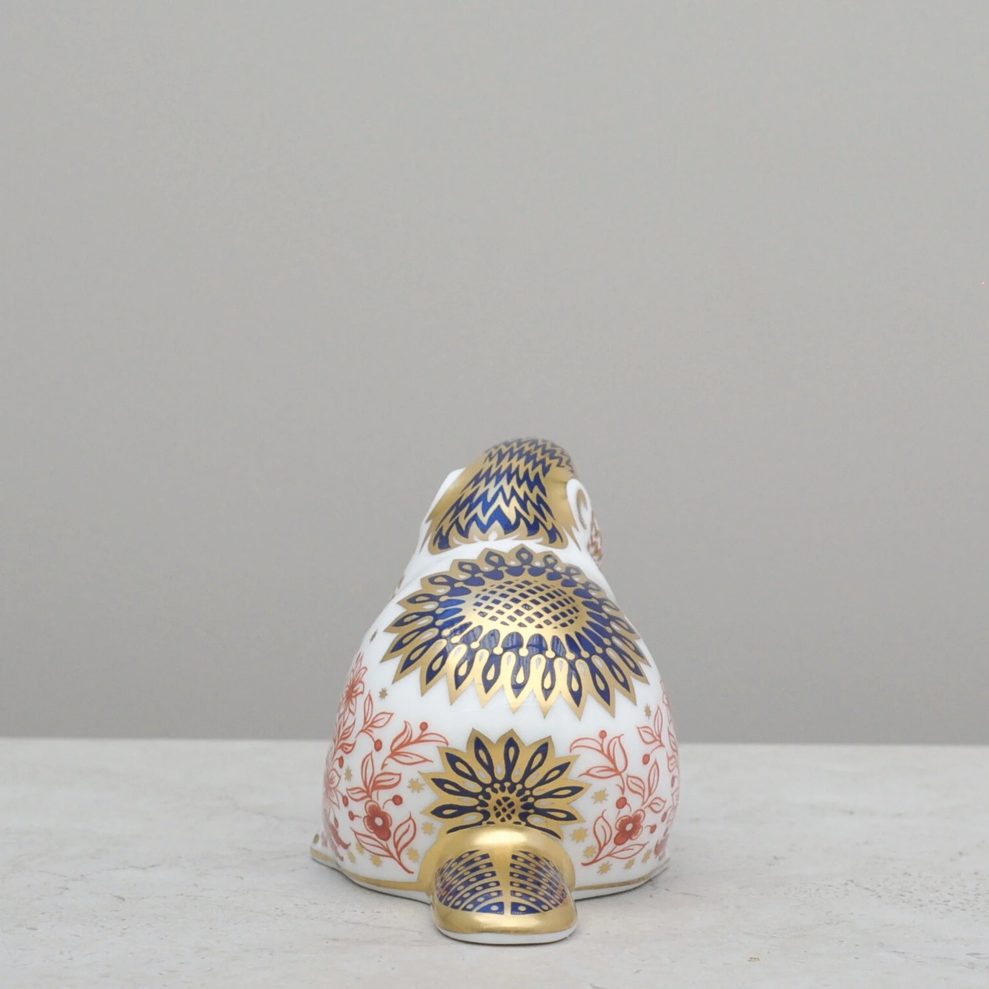Rear view of a Royal Crown Derby beaver paperweight showcasing symmetrical red and gold pattern work.