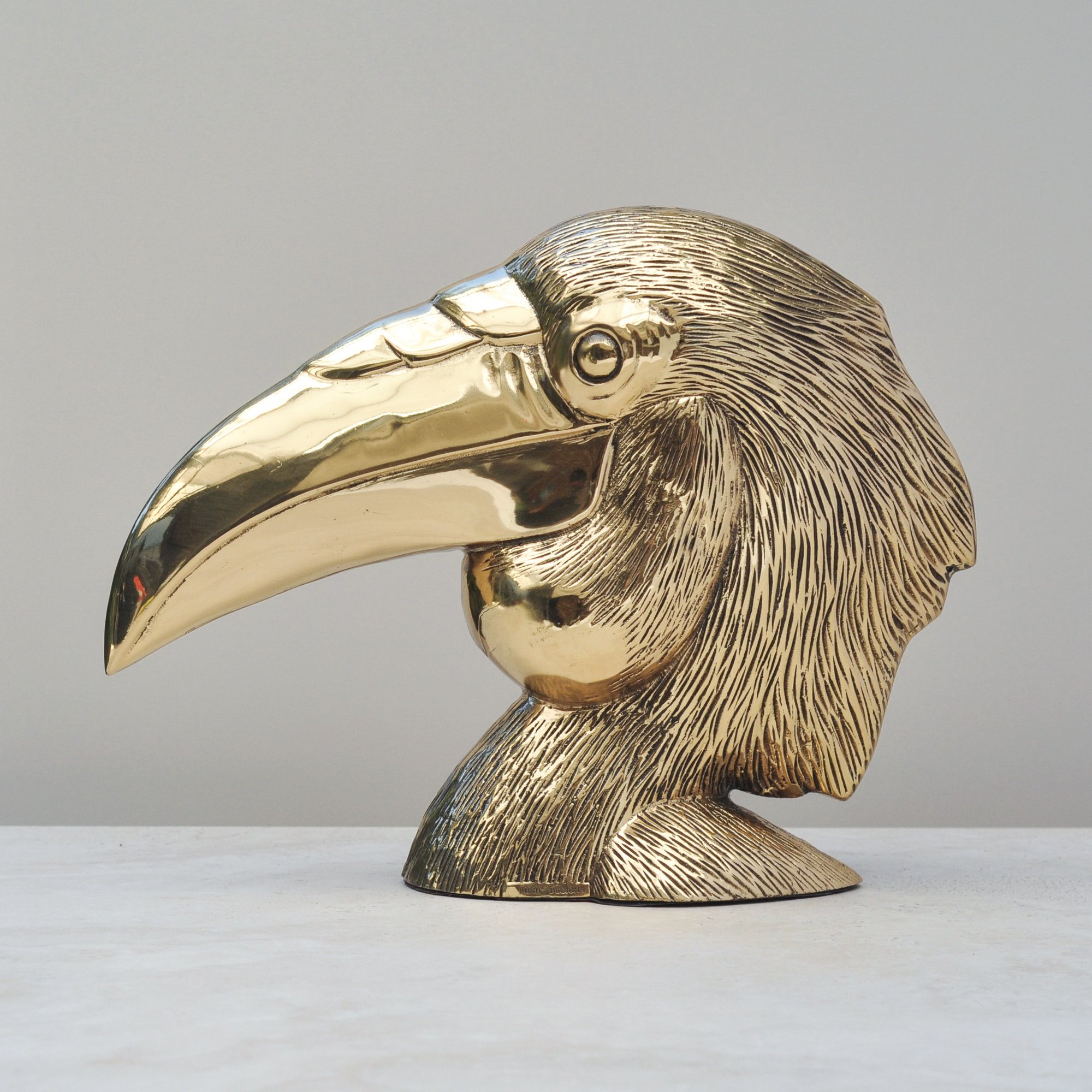 Vintage brass bird head sculpture with detailed feathers and polished beak