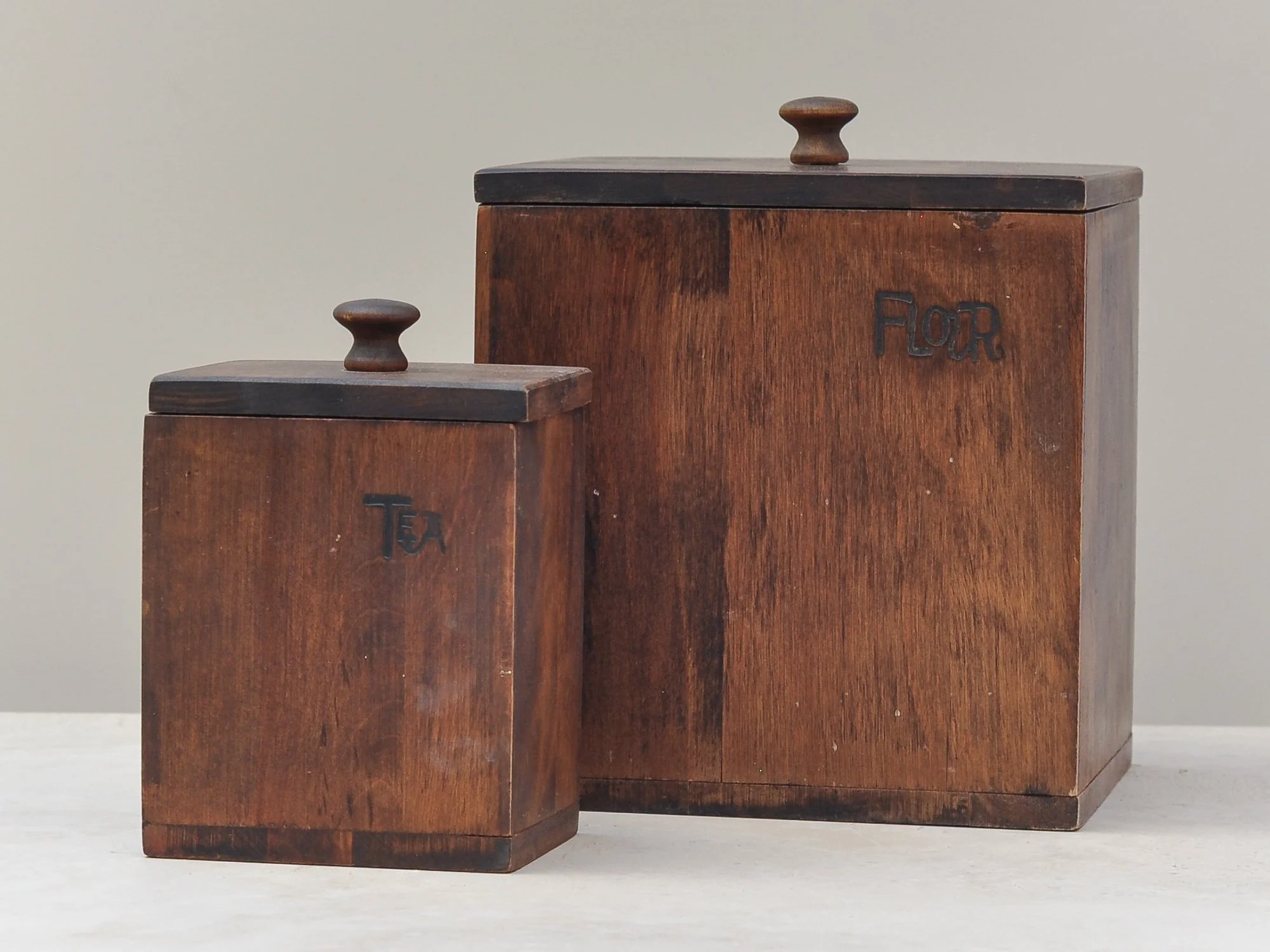Vintage wooden canisters for tea, flour and spice, grouped to show scale and hand-carved lettering.