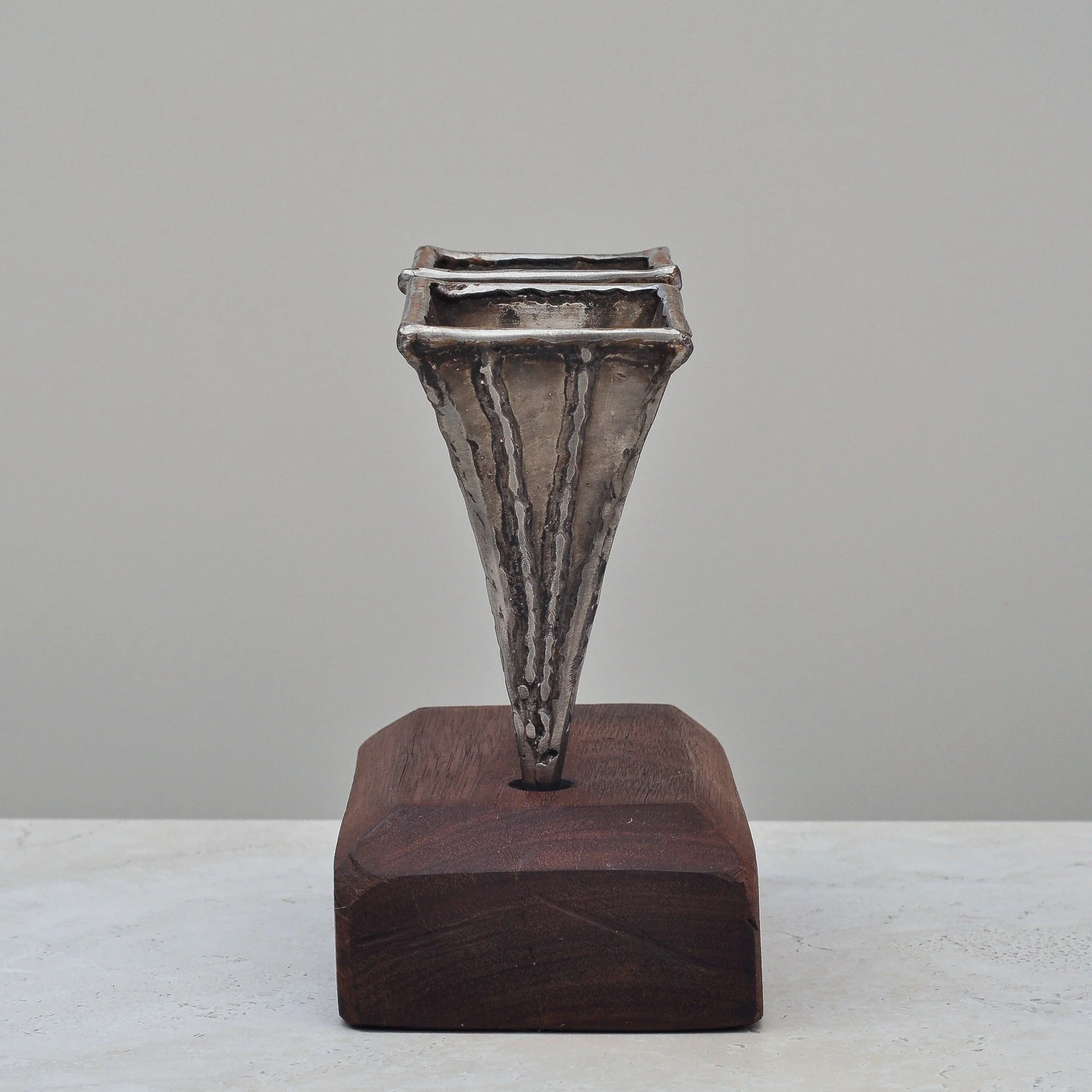 Single Brutalist metal vase by Nik Markovina on a wooden base, showcasing welded sculptural detailing.