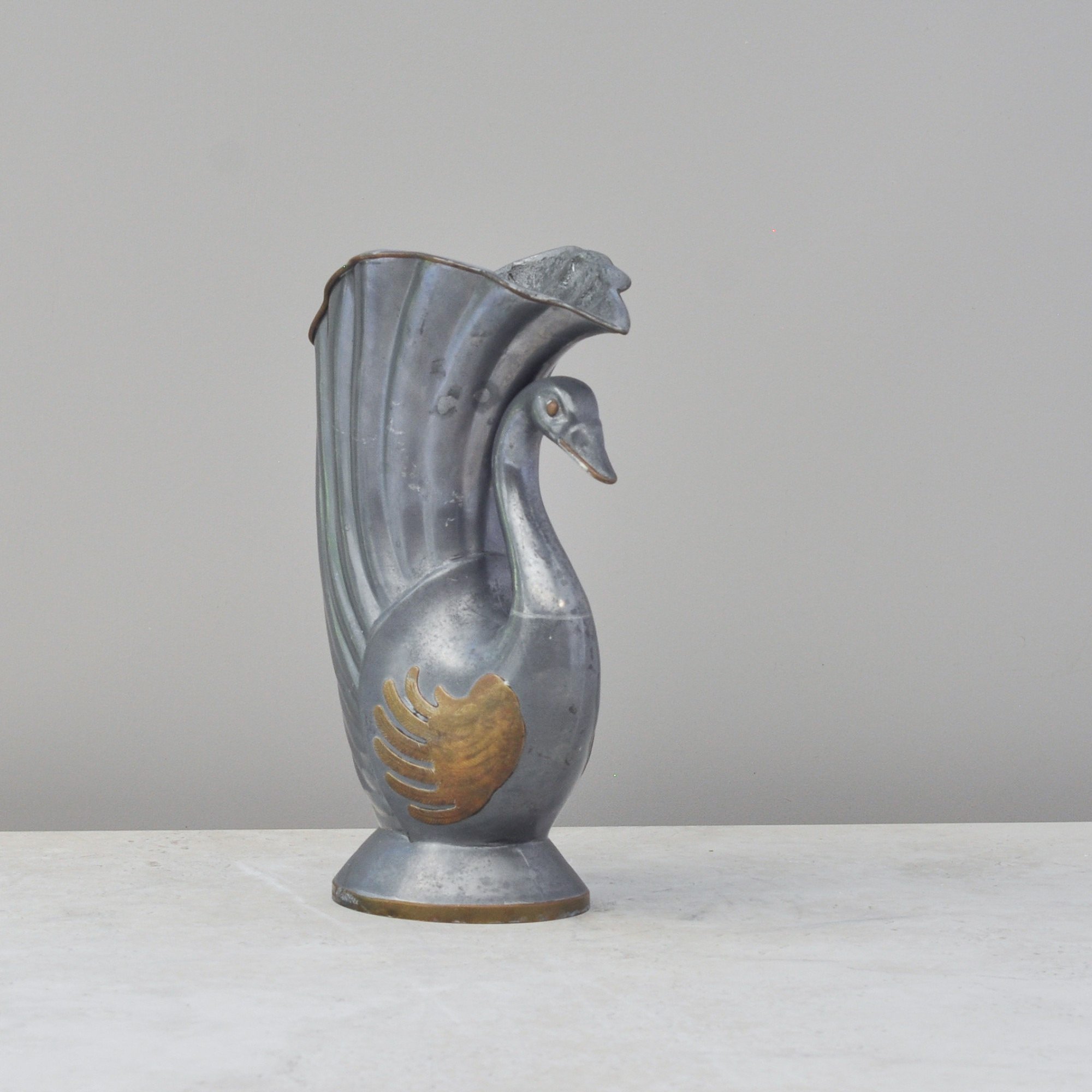 Side view of vintage pewter and brass swan vase