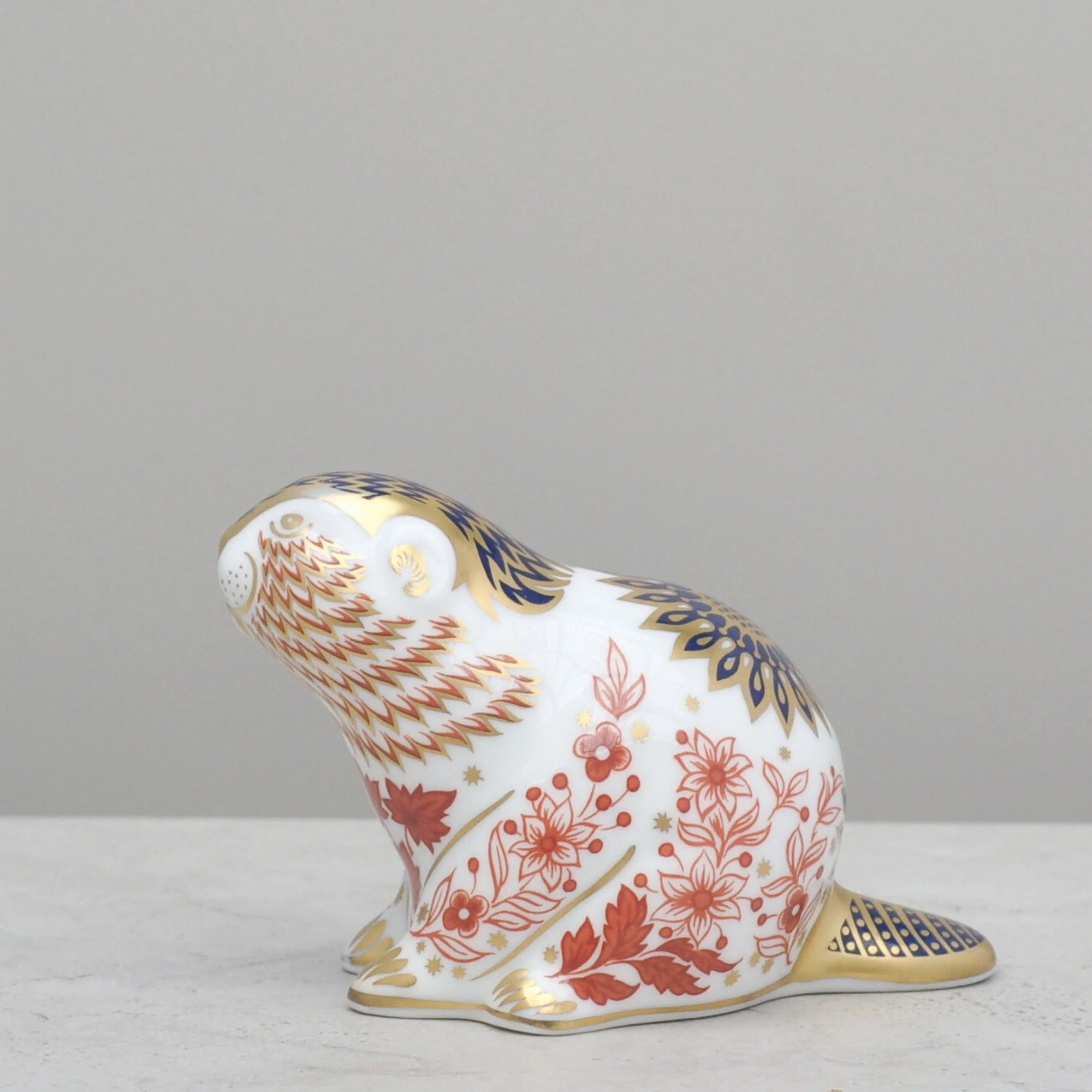 Front angled view of a Royal Crown Derby beaver paperweight featuring intricate red, blue and gold enamel detailing.