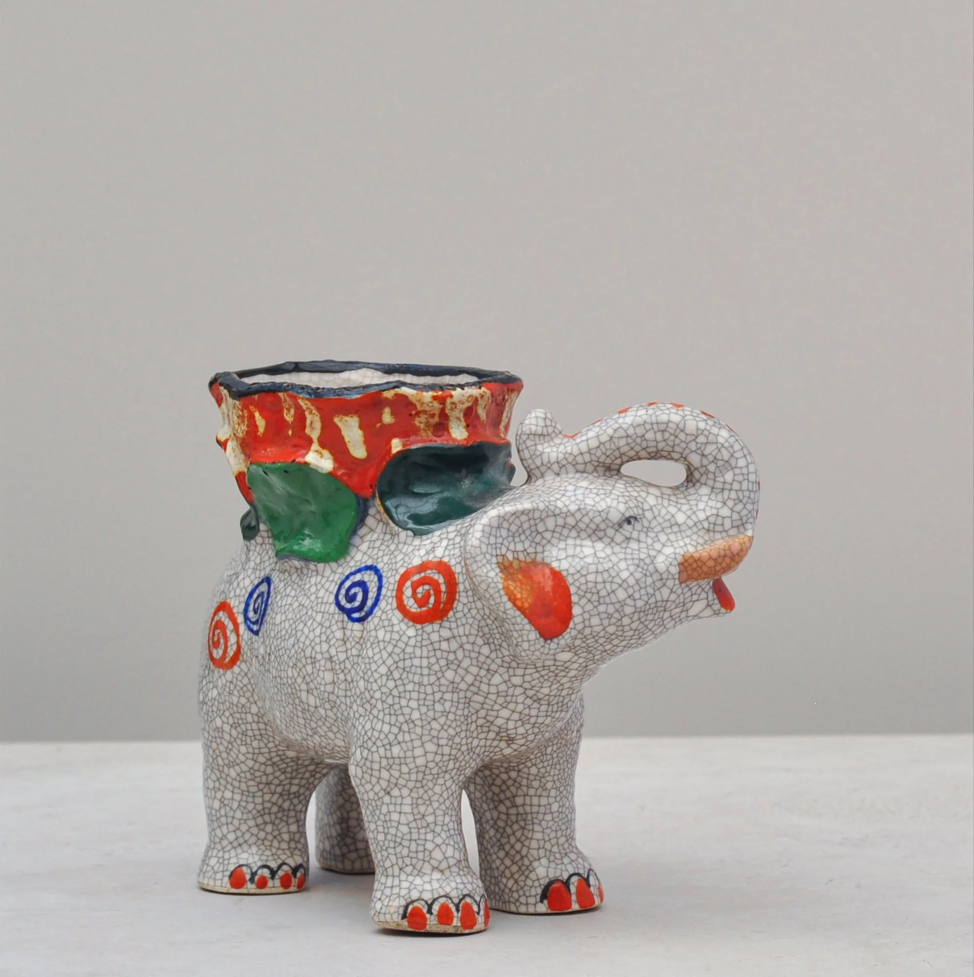 Hand-painted ceramic elephant vessel with a crackle-glaze finish, shown from a slight front angle.
