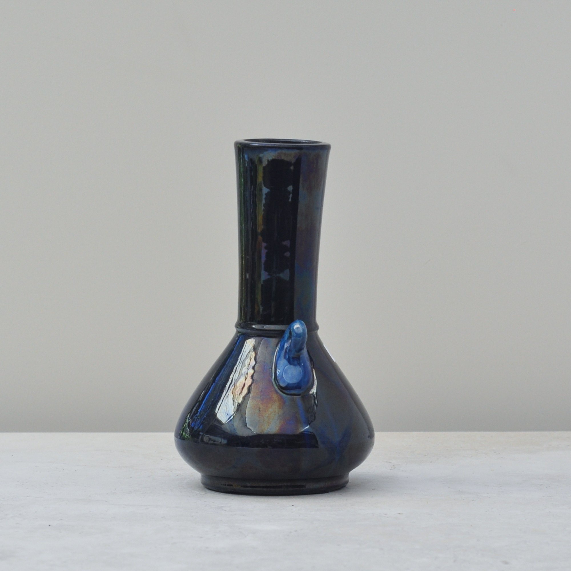 Close view of Japanese art pottery vase highlighting iridescent blue glaze and surface texture