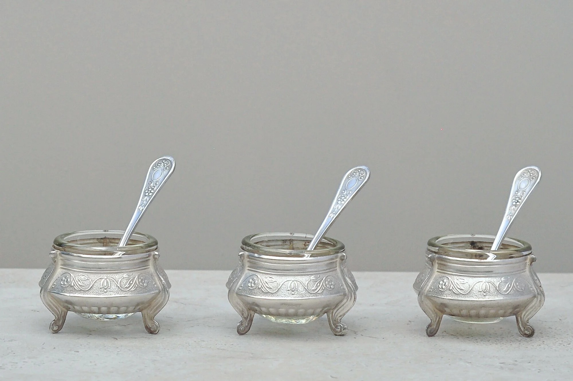 Mid-century Russian silver-plated salt cellars with original glass liners and matching spoons by IOMMET – full trio front view.