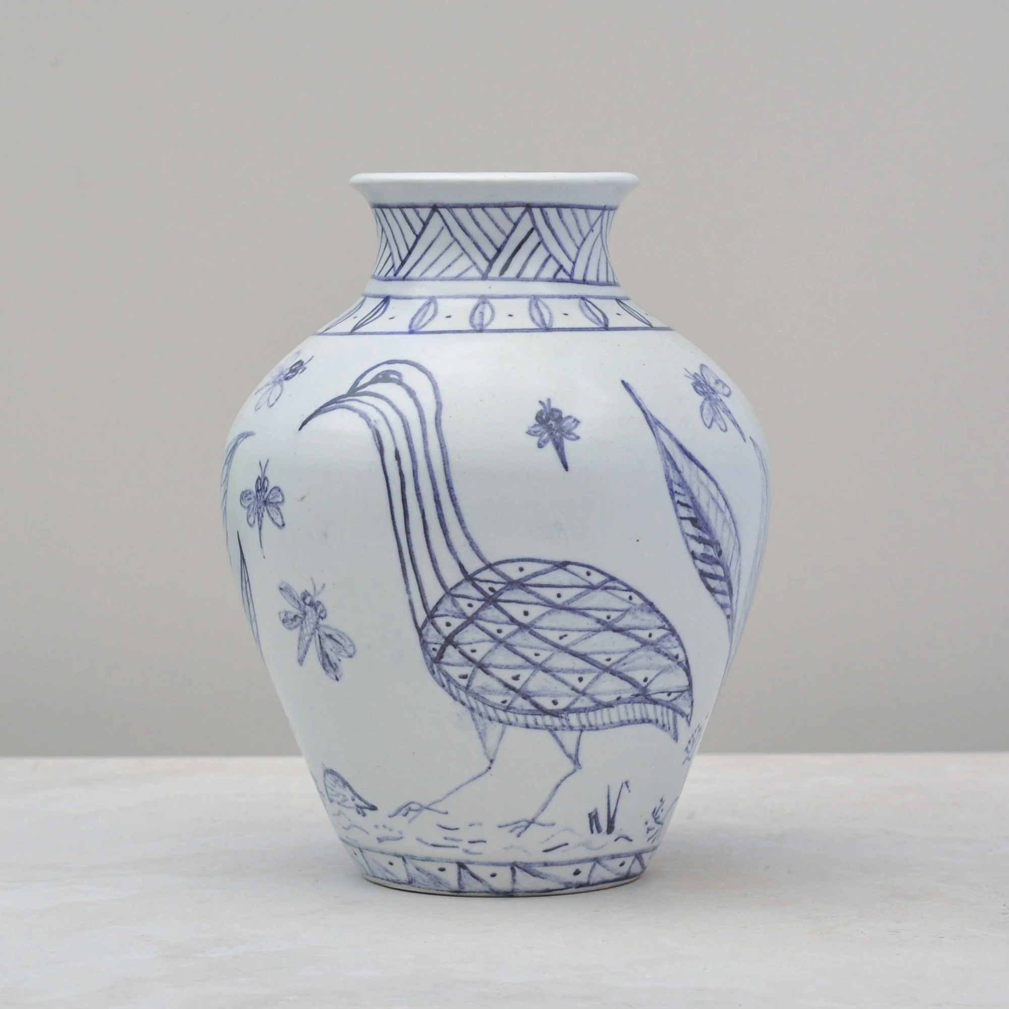 Blue and white vintage vase shown from the left side, highlighting hand-painted botanical and bird details.