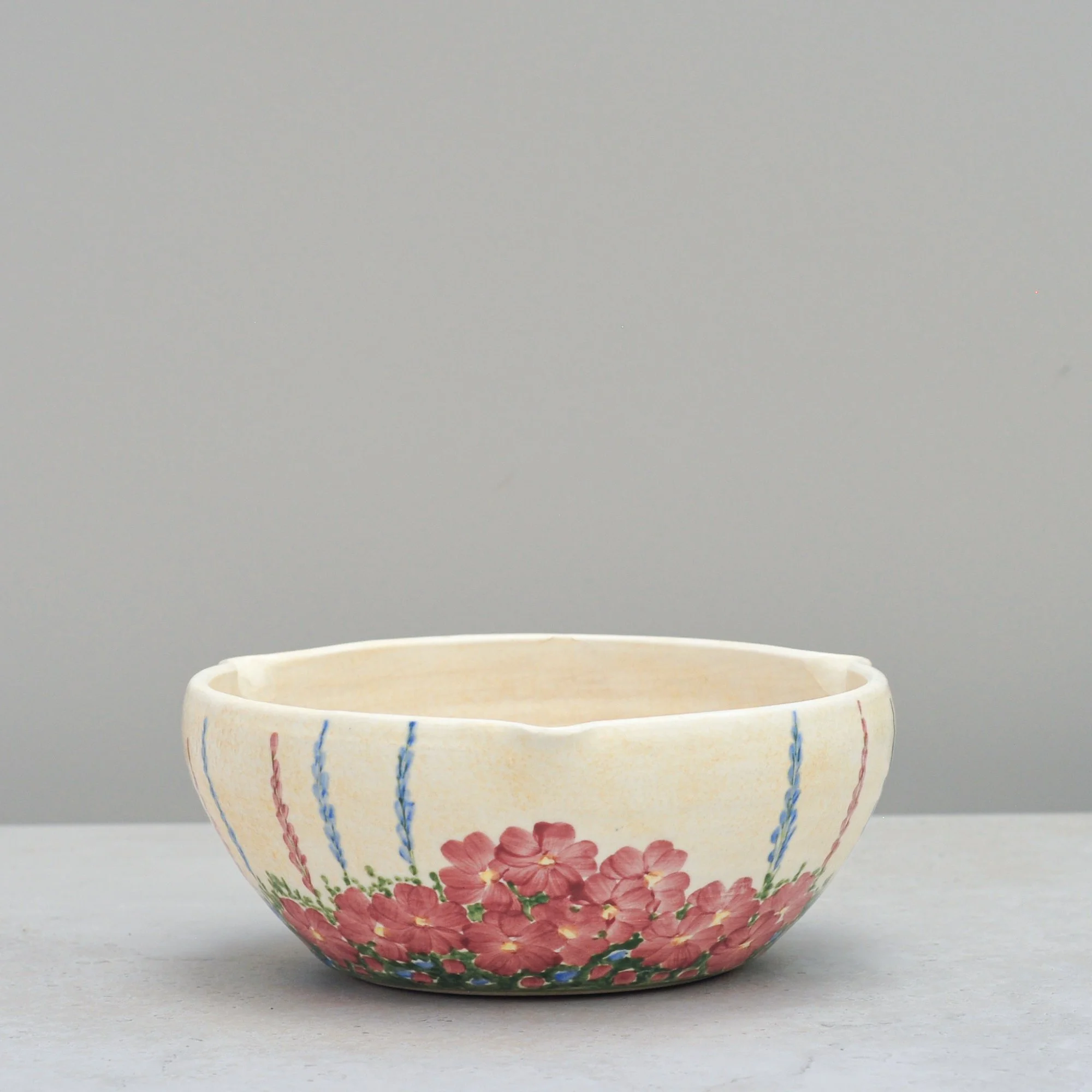 Art Deco E. Radford ceramic mixing bowl with hand-painted floral decoration, shown in an angled alternate view.