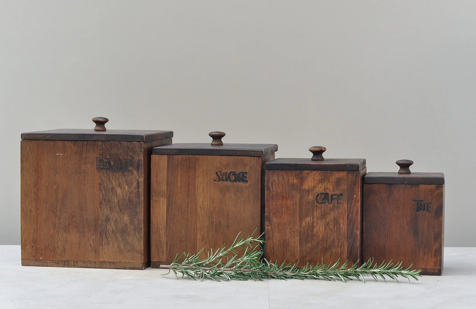 Vintage wooden canister set styled with fresh greenery, highlighting warm tones and hand-carved labels.