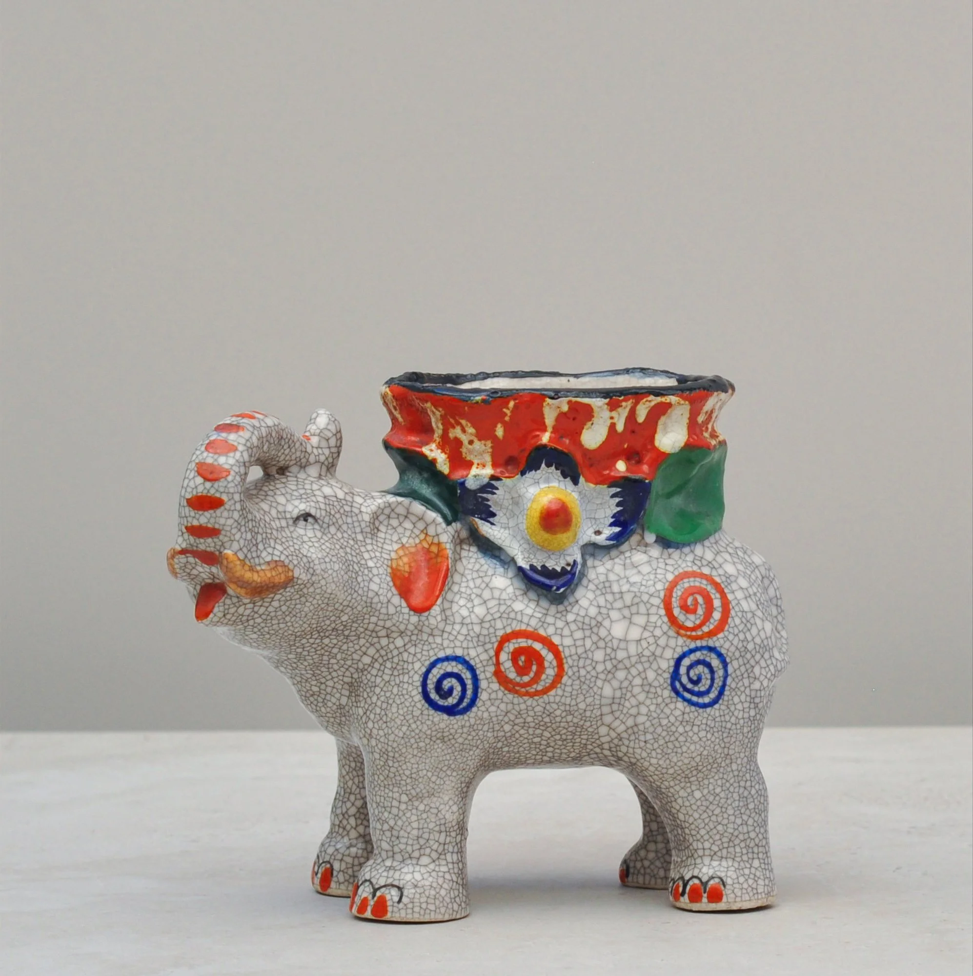 Hand-painted crackle-glazed elephant vessel with colourful floral and swirl motifs, front angled view.