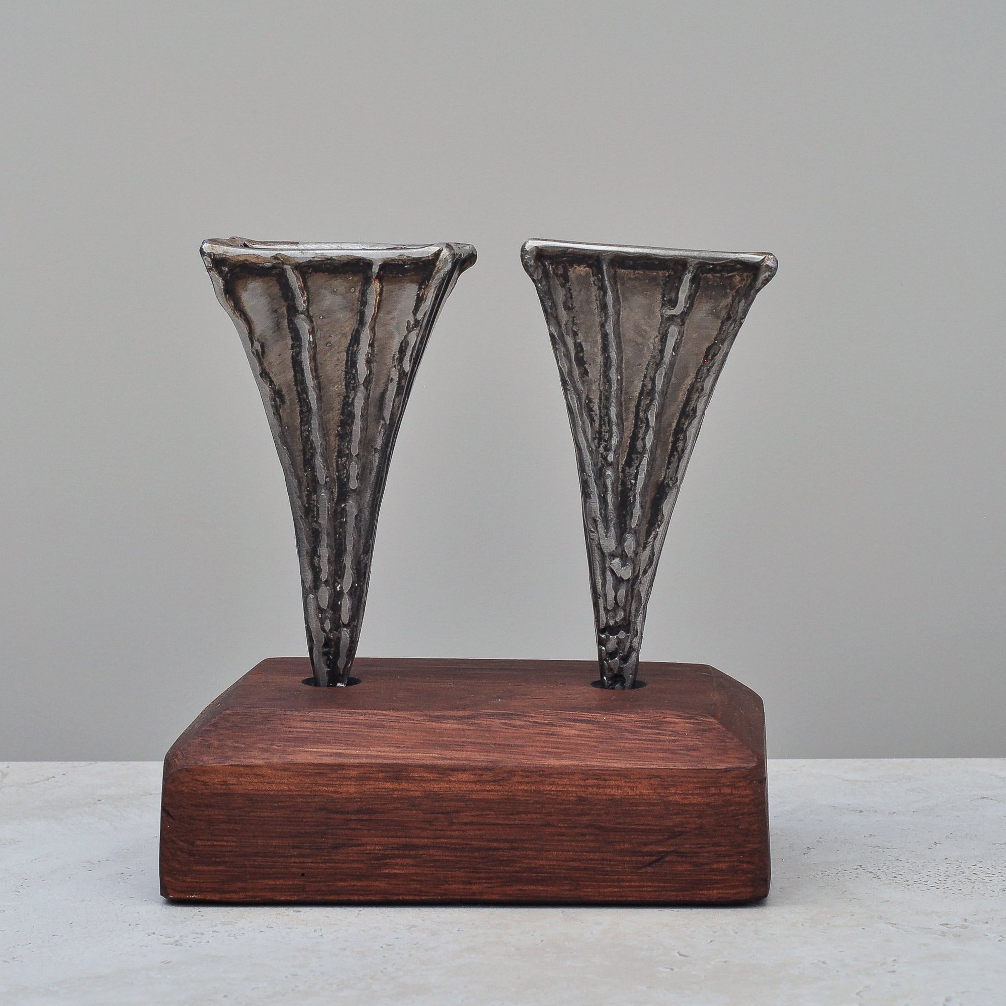 Single Brutalist metal vase by Nik Markovina on a wooden base, showcasing welded sculptural detailing.