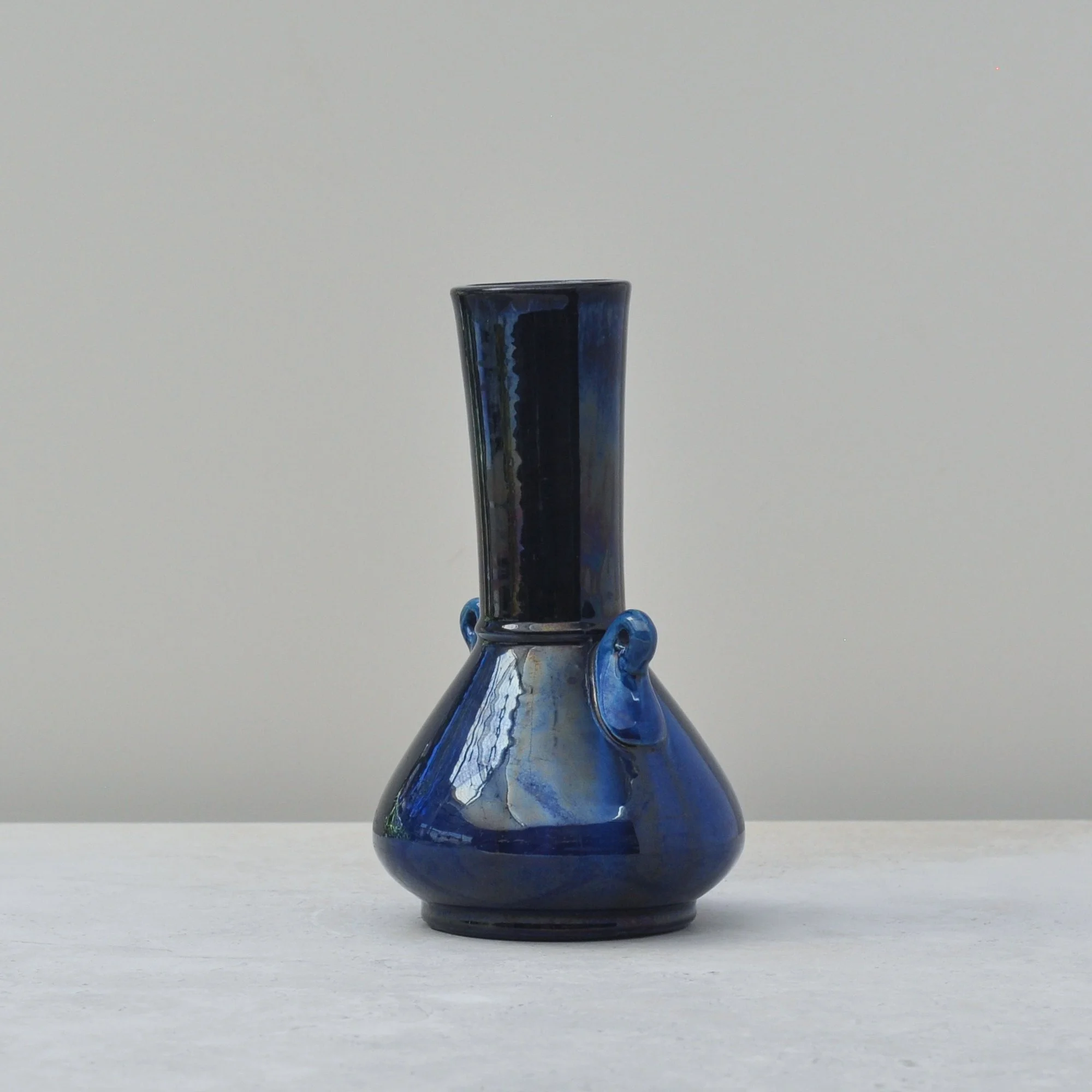 Side view of Japanese blue iridescent art pottery vase showing subtle vertical drip movement