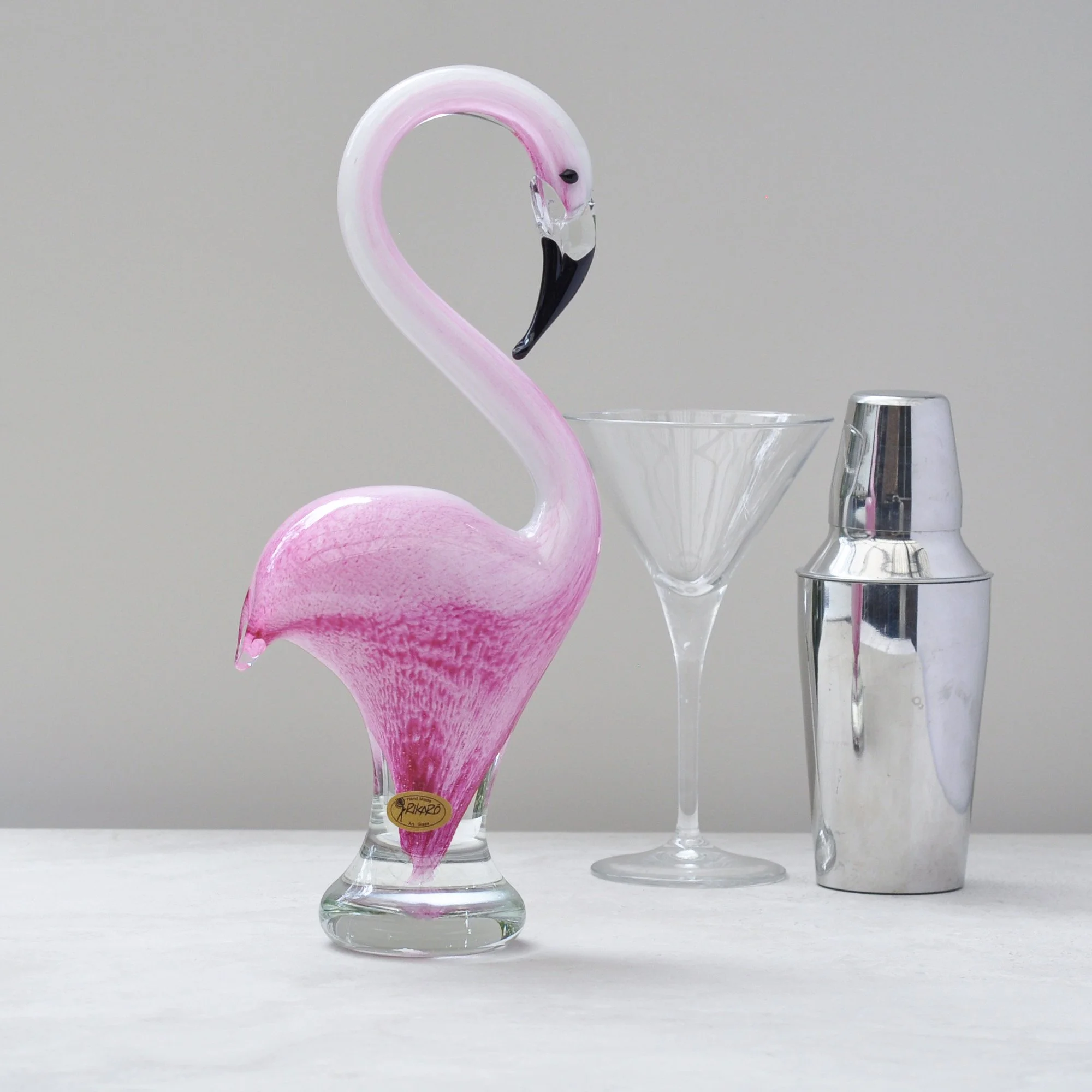 Hand blown pink glass flamingo styled with cocktail glass and shaker on a bar cart