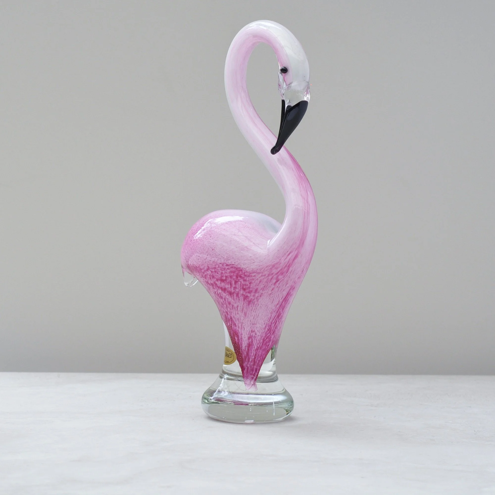 Side view of hand blown glass flamingo showing curved neck and textured pink body