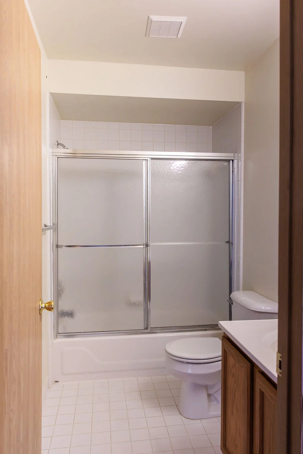 Bathroom with a glass sliding shower door, white toilet, and wooden vanity with a sink