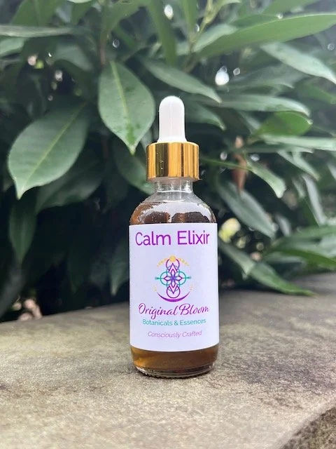 A small glass dropper bottle labeled 'Calm Elixir' from Original Bloom Botanicals & Essences, featuring a gold cap and a white dropper, placed outdoors on a wooden surface with green leafy plants in the background.