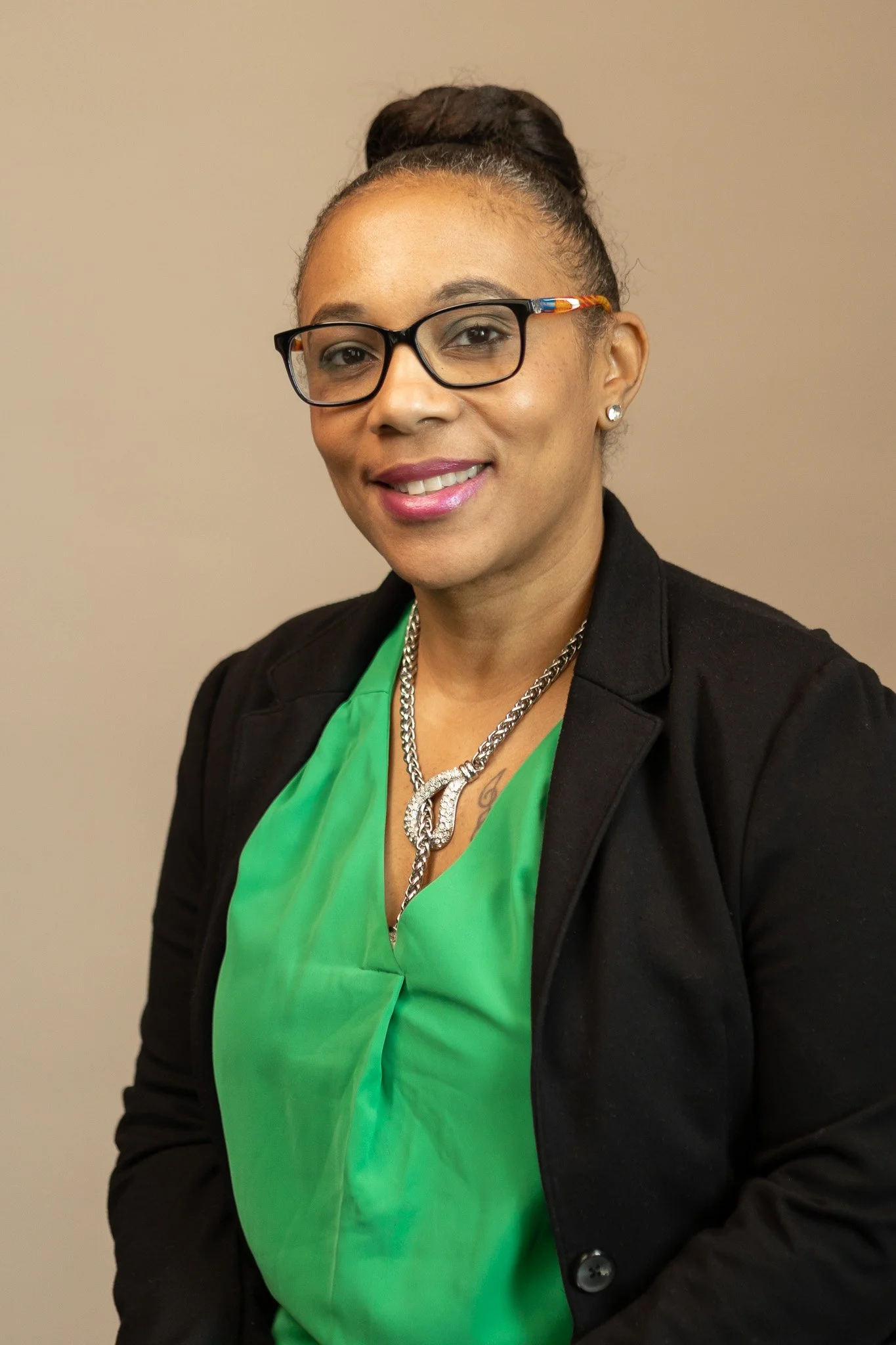 A woman with glasses, a black blazer, a green blouse, and a silver necklace, smiling at the camera. Stephanie Garvin, LPC