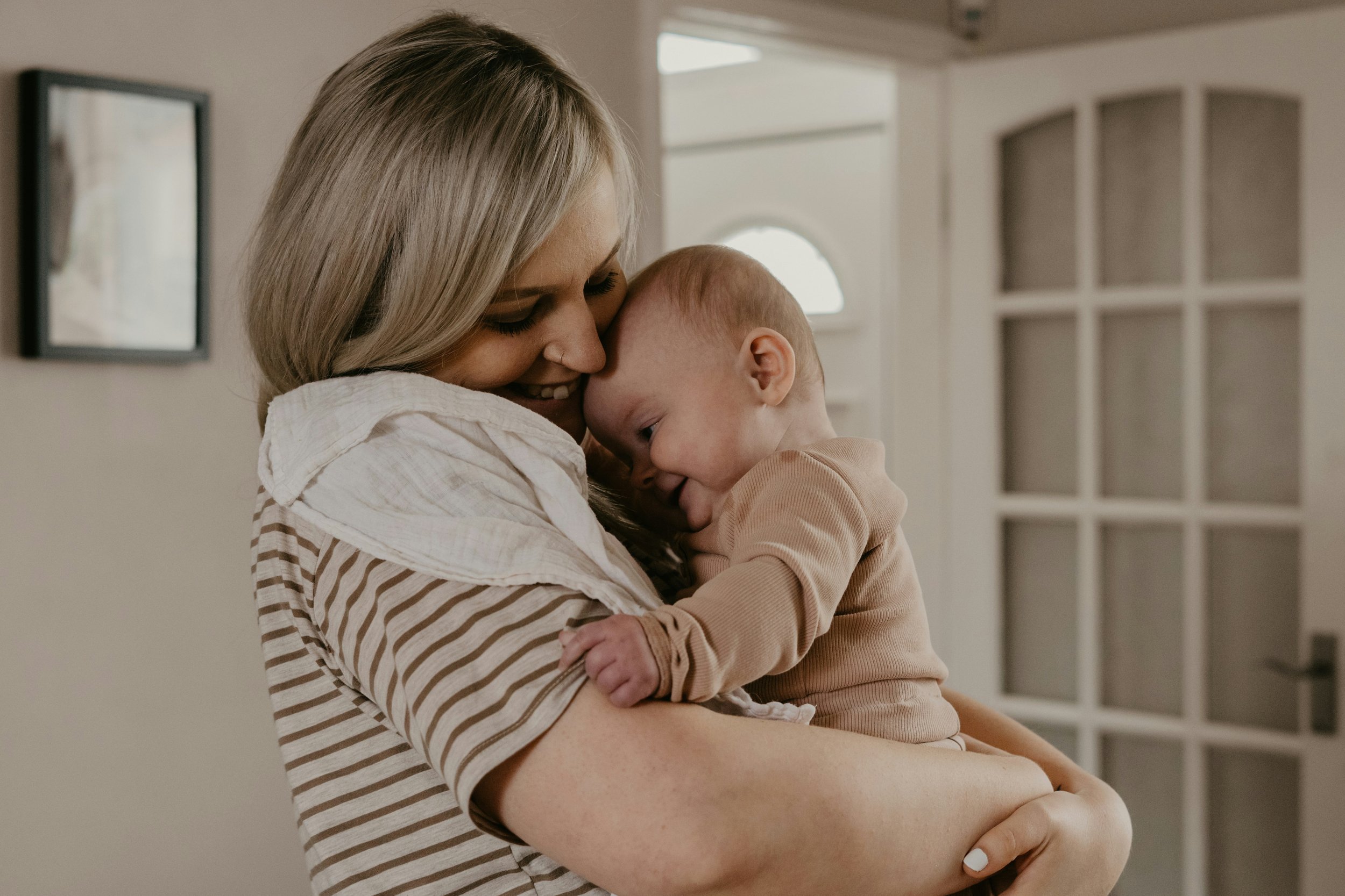 Mother holding baby and laughing softly.