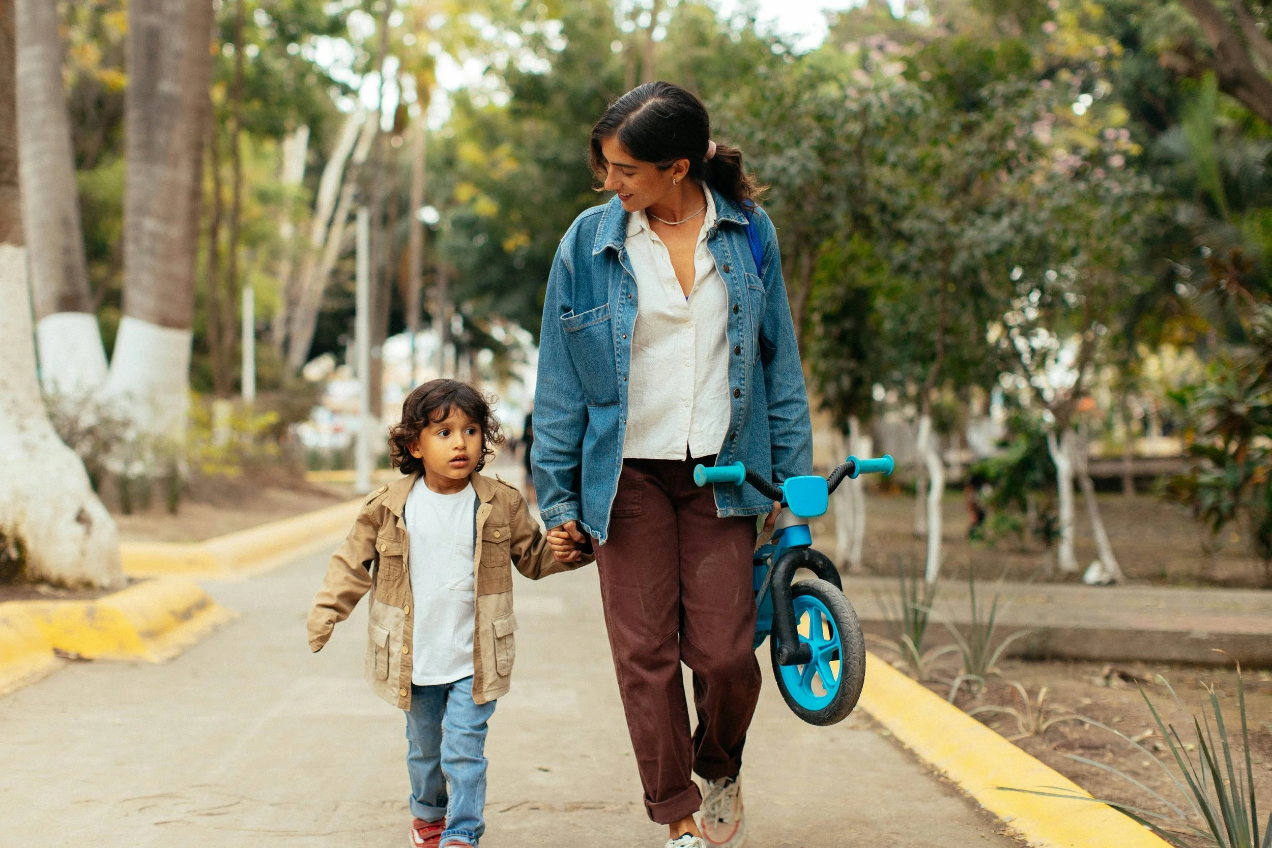 Mother walking with son holding his bicycle.