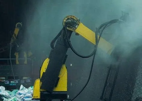A robotic arm with a yellow and black color scheme operating in a manufacturing or industrial setting, surrounded by smoke or dust.