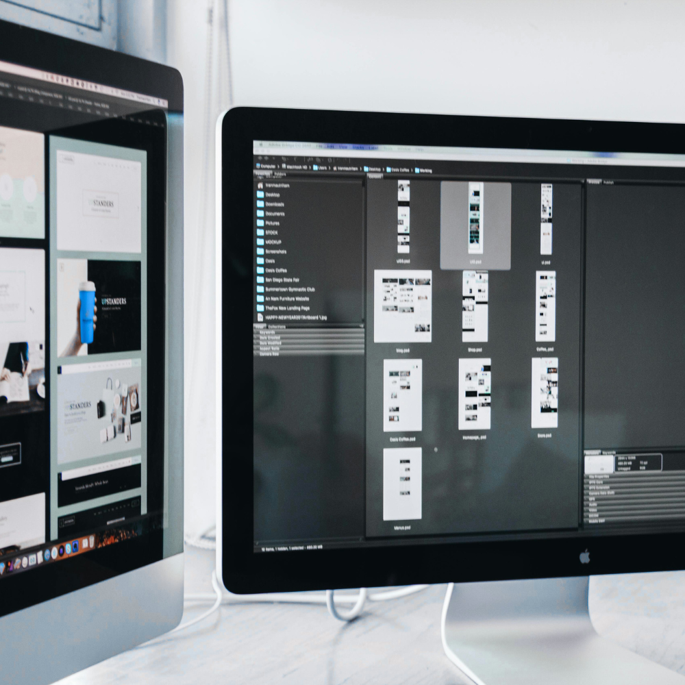 Two computer monitors displaying digital design and photo editing software, with files and images on the screens.
