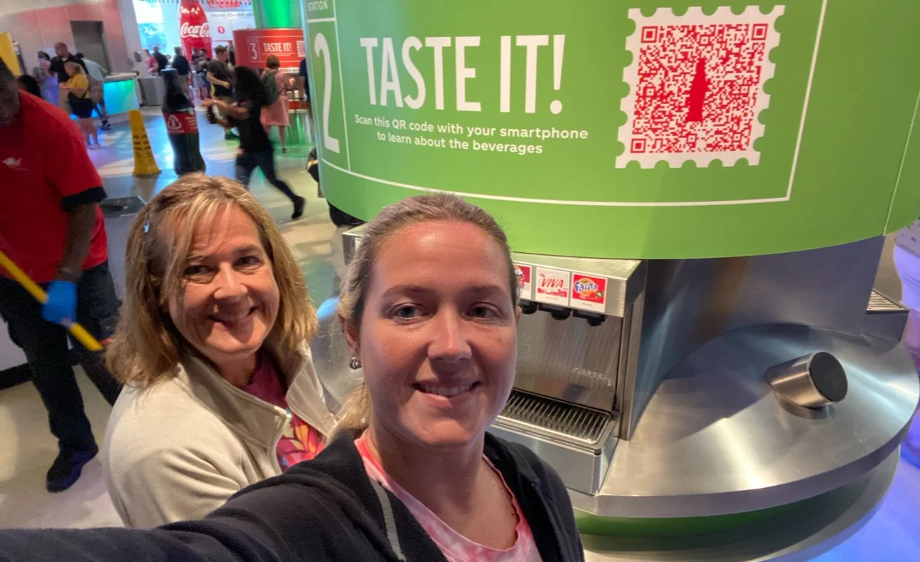 Two women sampling different Coca-Cola beverages inside the World of Coca-Cola Museum.