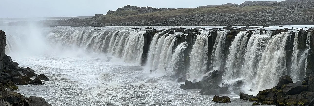 The wide, cascading Selfoss waterfall in Iceland surrounded by rocky terrain.
