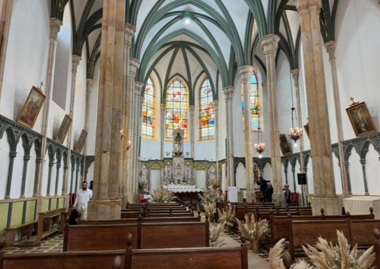 The interior of the church at Santuário do Caraça in Brazil, featuring ornate architecture, wooden pews, and stained glass windows.