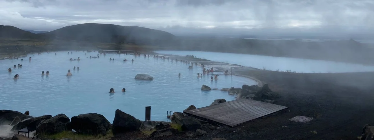 Relaxing in the Myvatn Nature Baths in Iceland with geothermal waters and steam rising in the background.