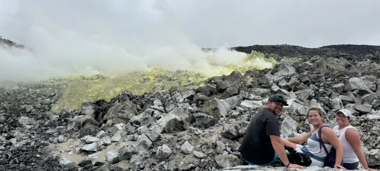 Three people standing in front of the steaming volcanic area on the Sierra Negra hike in the Galápagos Islands.