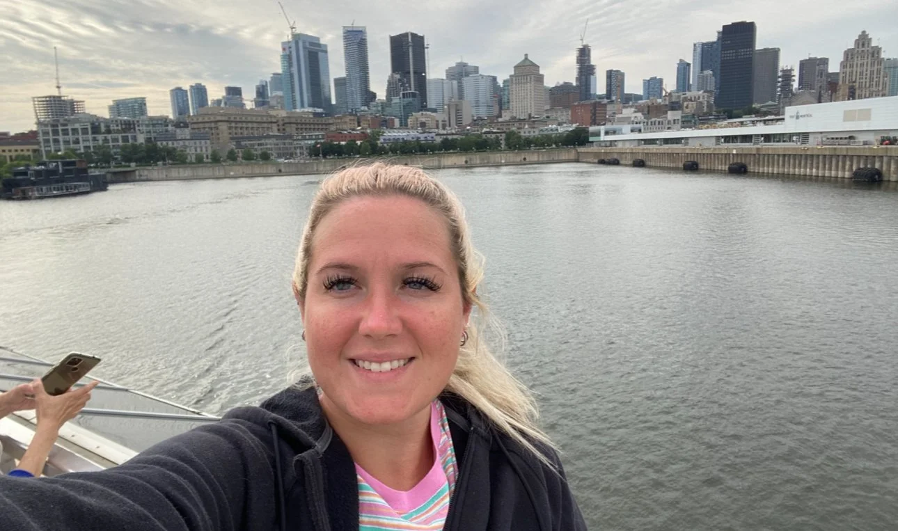 Woman taking a selfie on a guided river cruise in Montreal, with city skyline and waterfront views in the background.