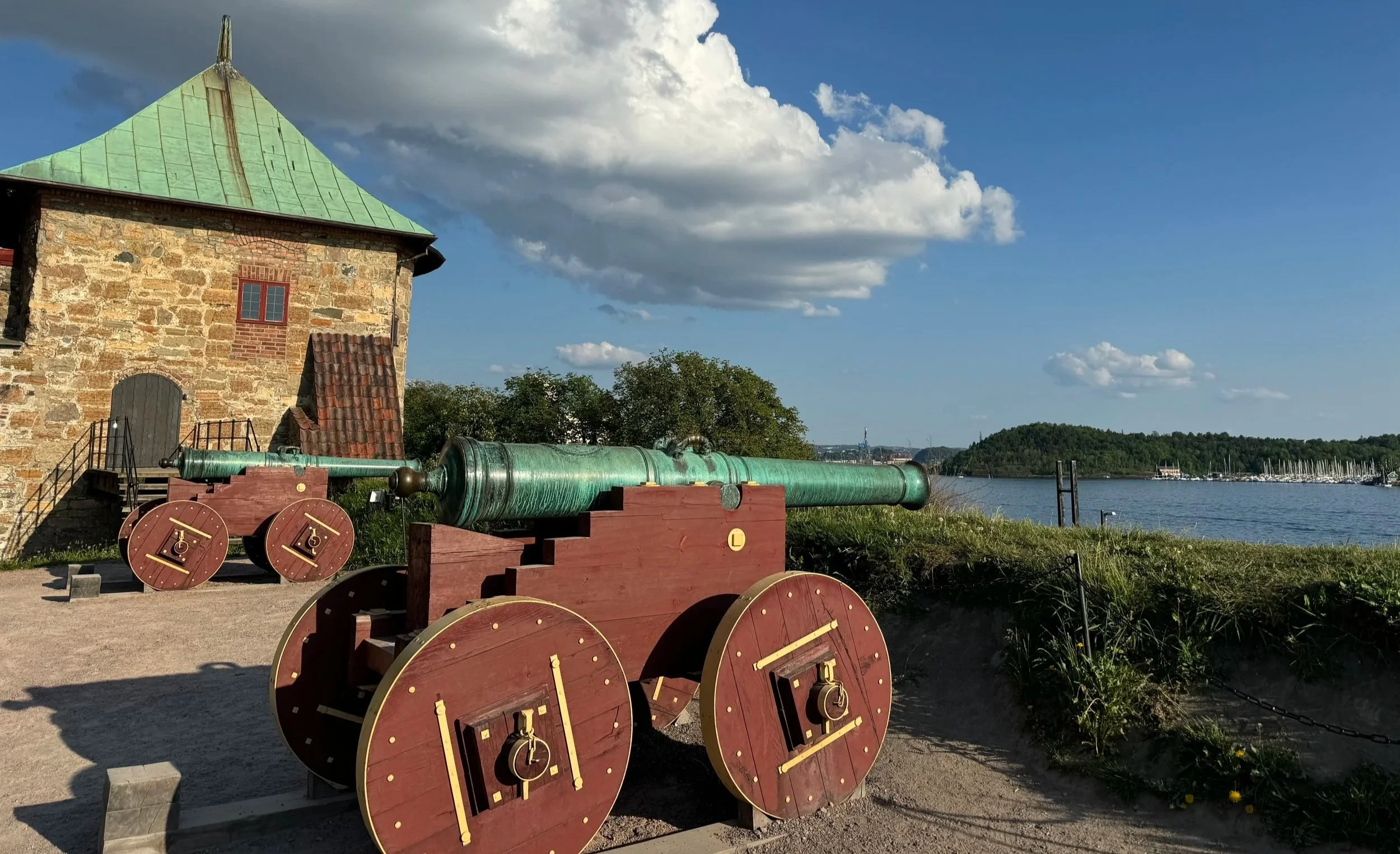 Historic cannon at Akershus Fortress overlooking Oslo Harbor, medieval stone walls and coastal views in Oslo, Norway
