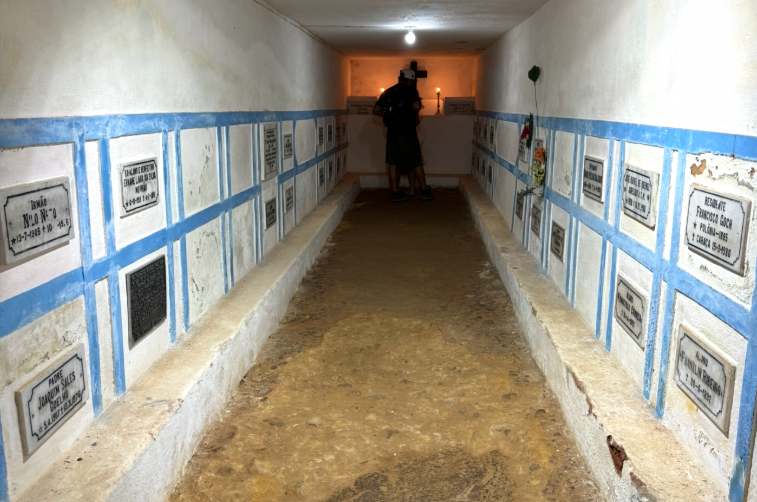 A man observing the catacombs at Santuário do Caraça in Brazil, surrounded by historic stone walls and passageways.