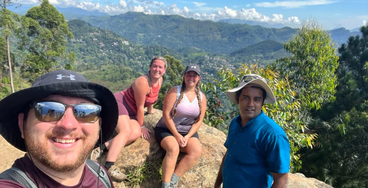 Three hikers with their guide pausing at the top of Ella Rock hike in Sri Lanka.