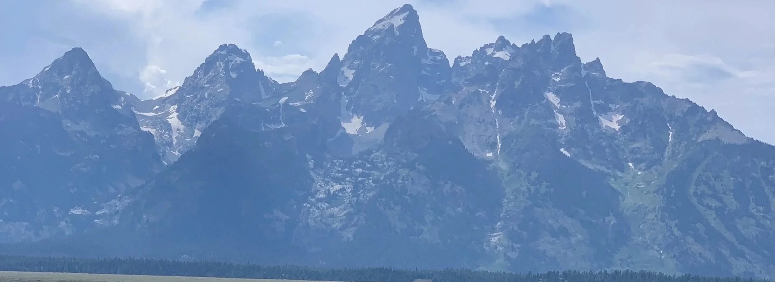 Majestic view of the Grand Teton rising above the valley with soft light highlighting the rugged mountain peaks.